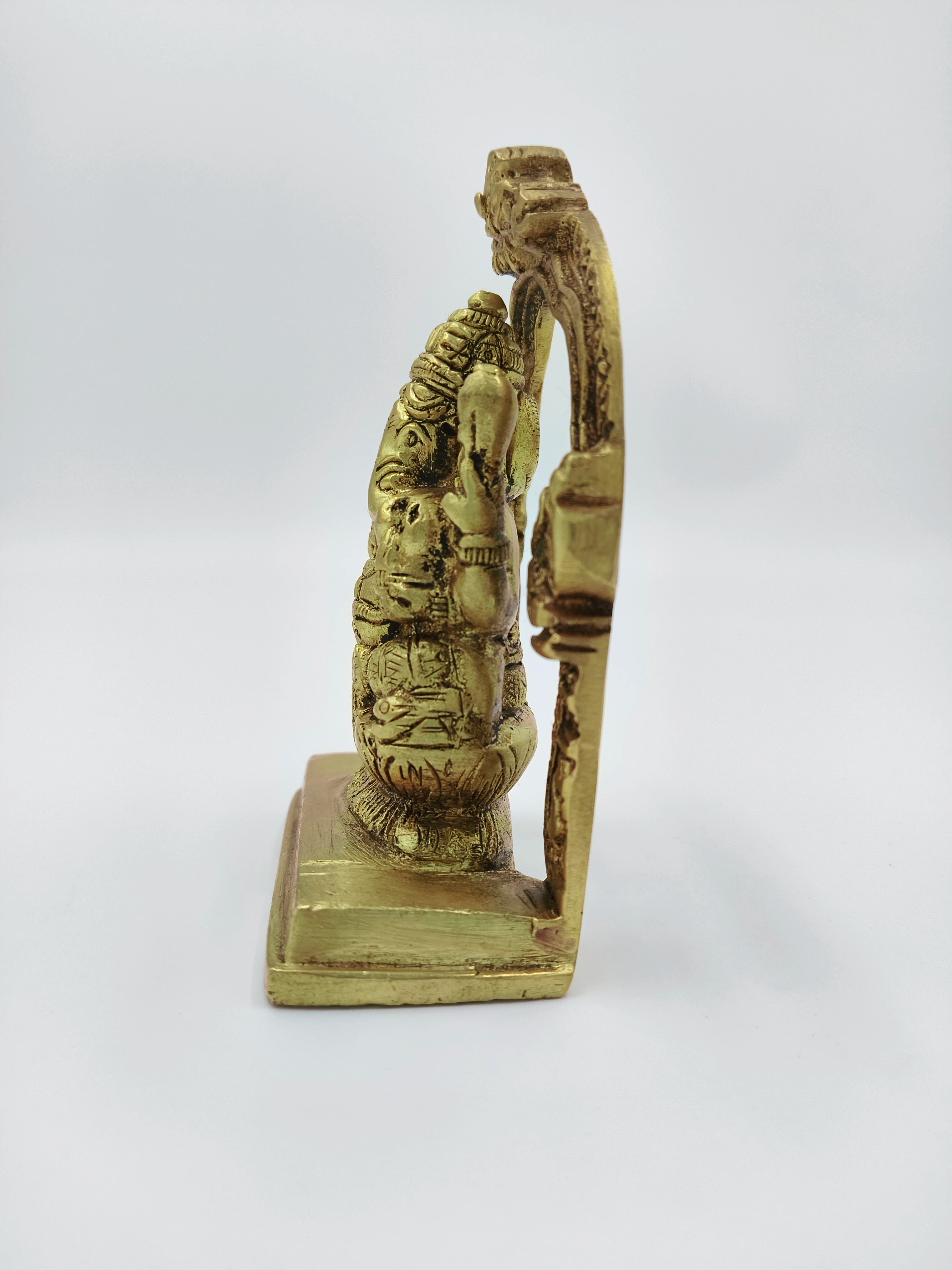 Side view of small brass Ganesh sculpture with decorative arch on base