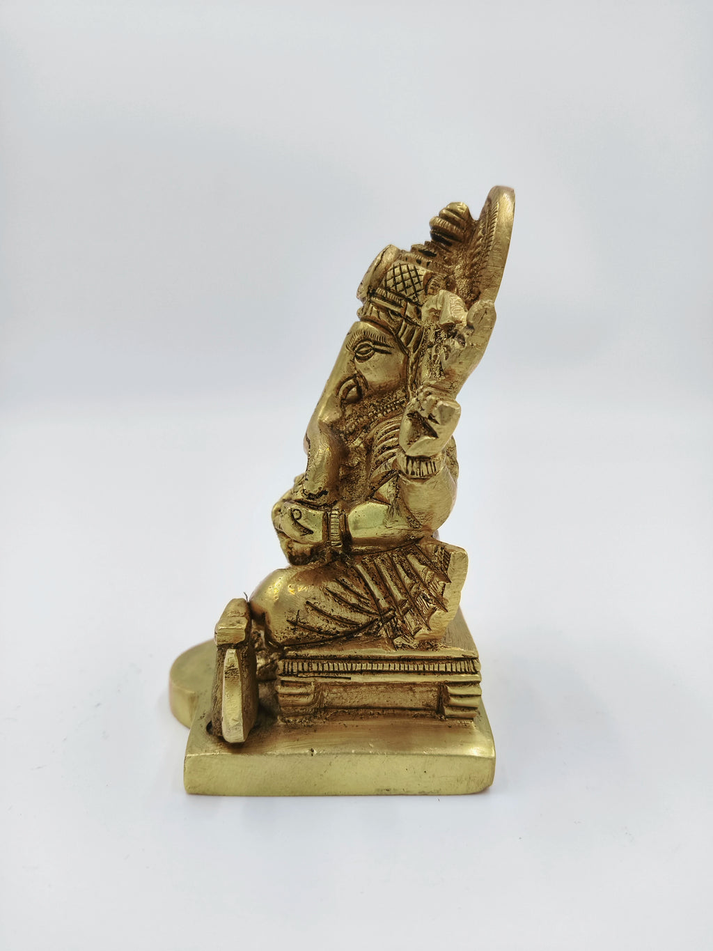 side view of small brass Siddhi Vinayaka Ganesh statue sitting on pedestal