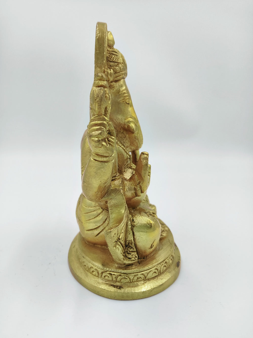 Side view of medium brass Padmasana Ganapati statue seated on ornate base