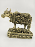 Brass sculpture of a cow and calf with intricate spiritual engravings on a decorated base