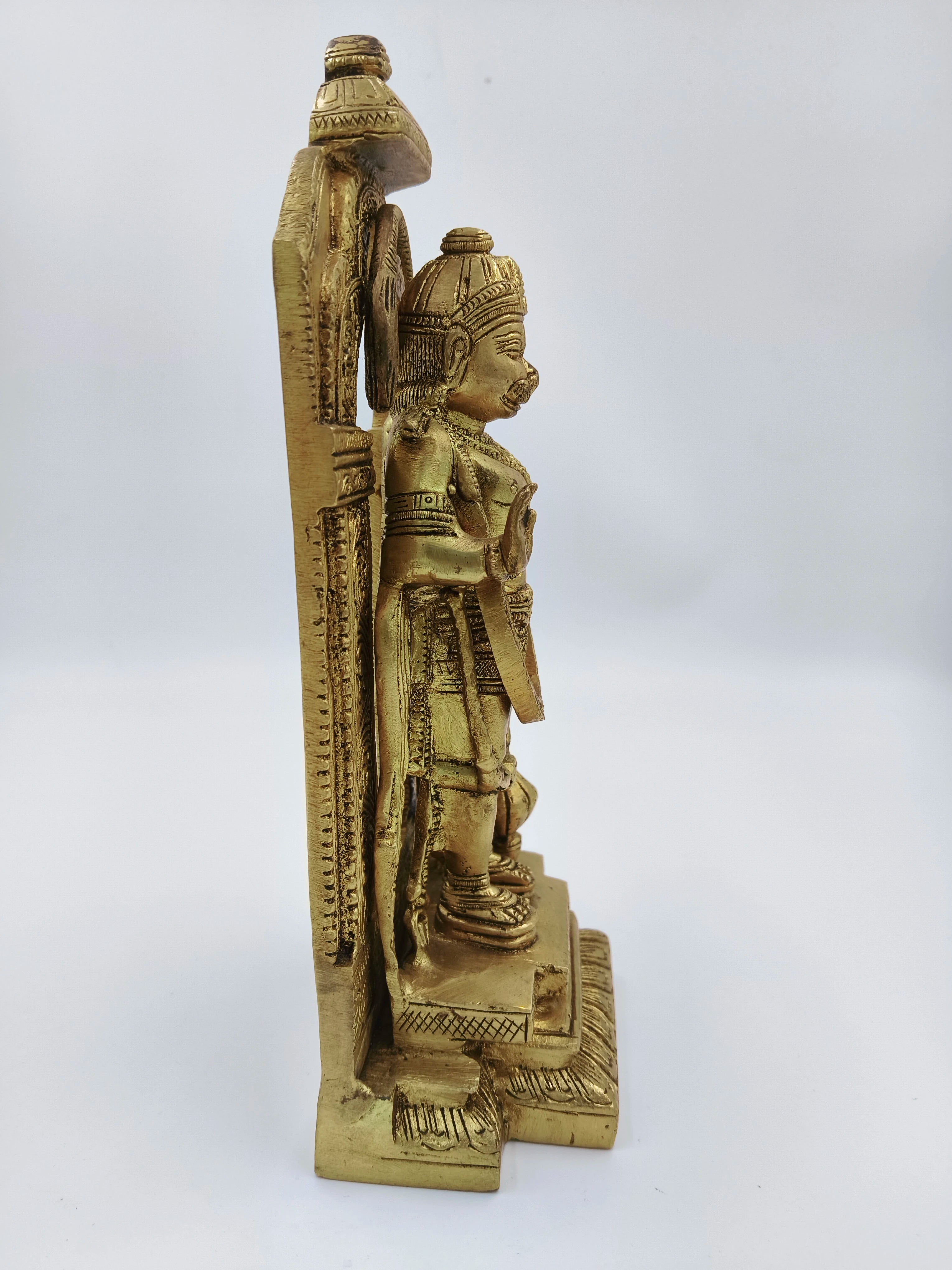Side view of brass standing Hanuman sculpture with detailed arch backdrop