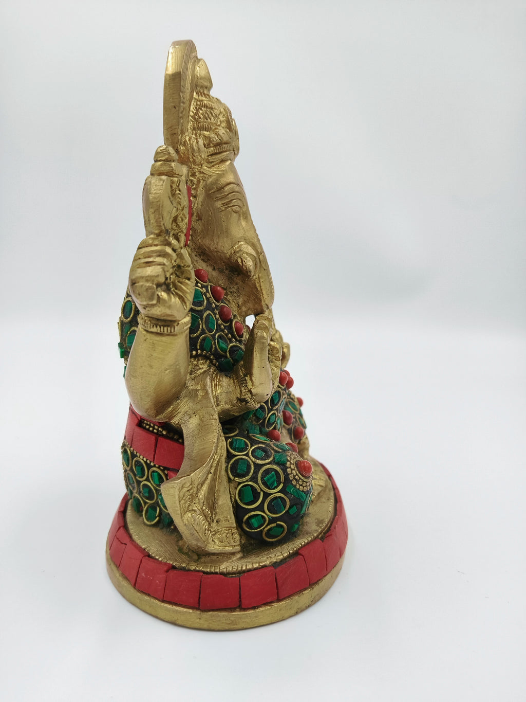 Side view of brass Ganesh sculpture with red and green decorative stones