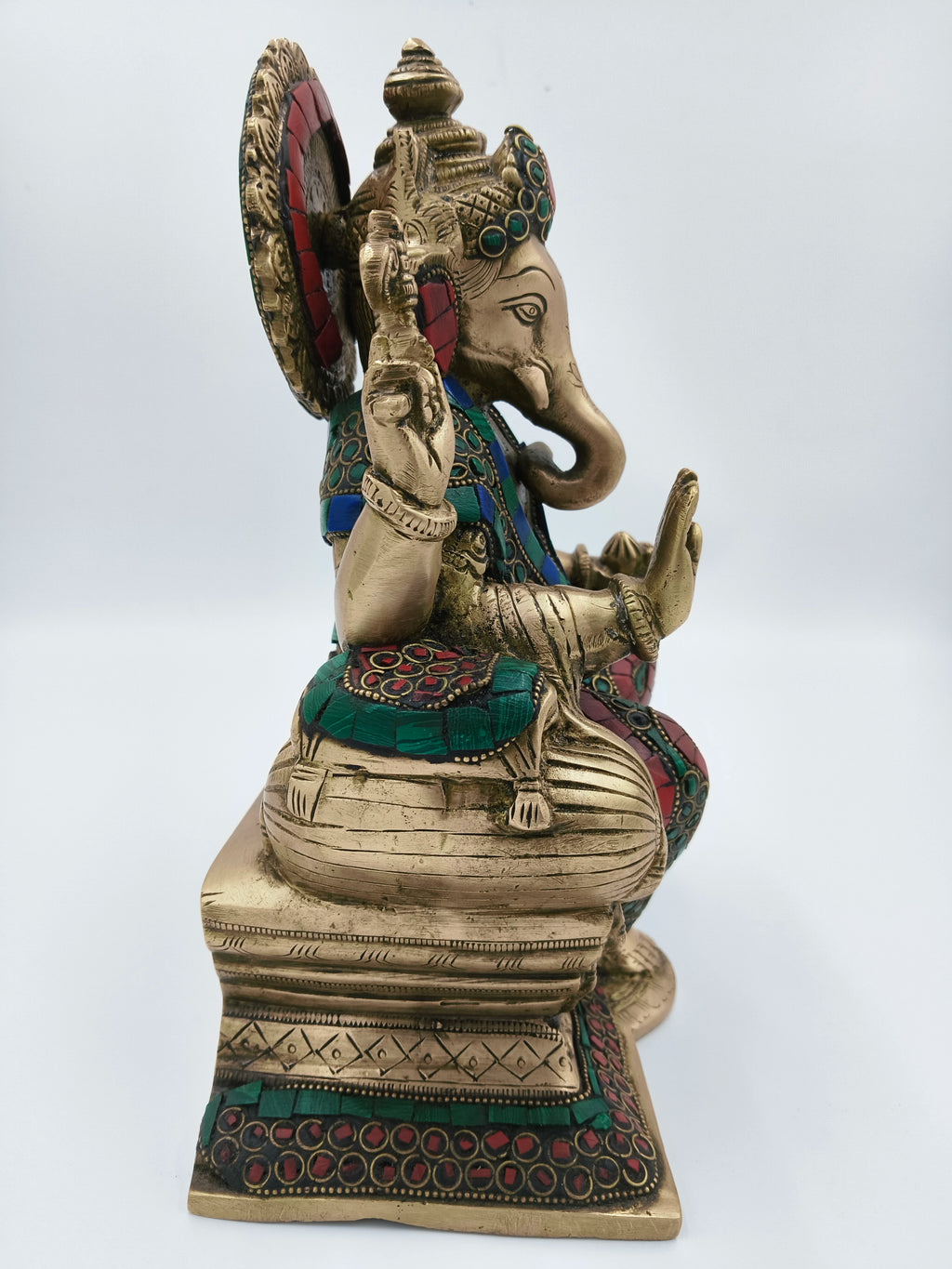 Side view of large brass Ganesh statue with red and green decorative accents