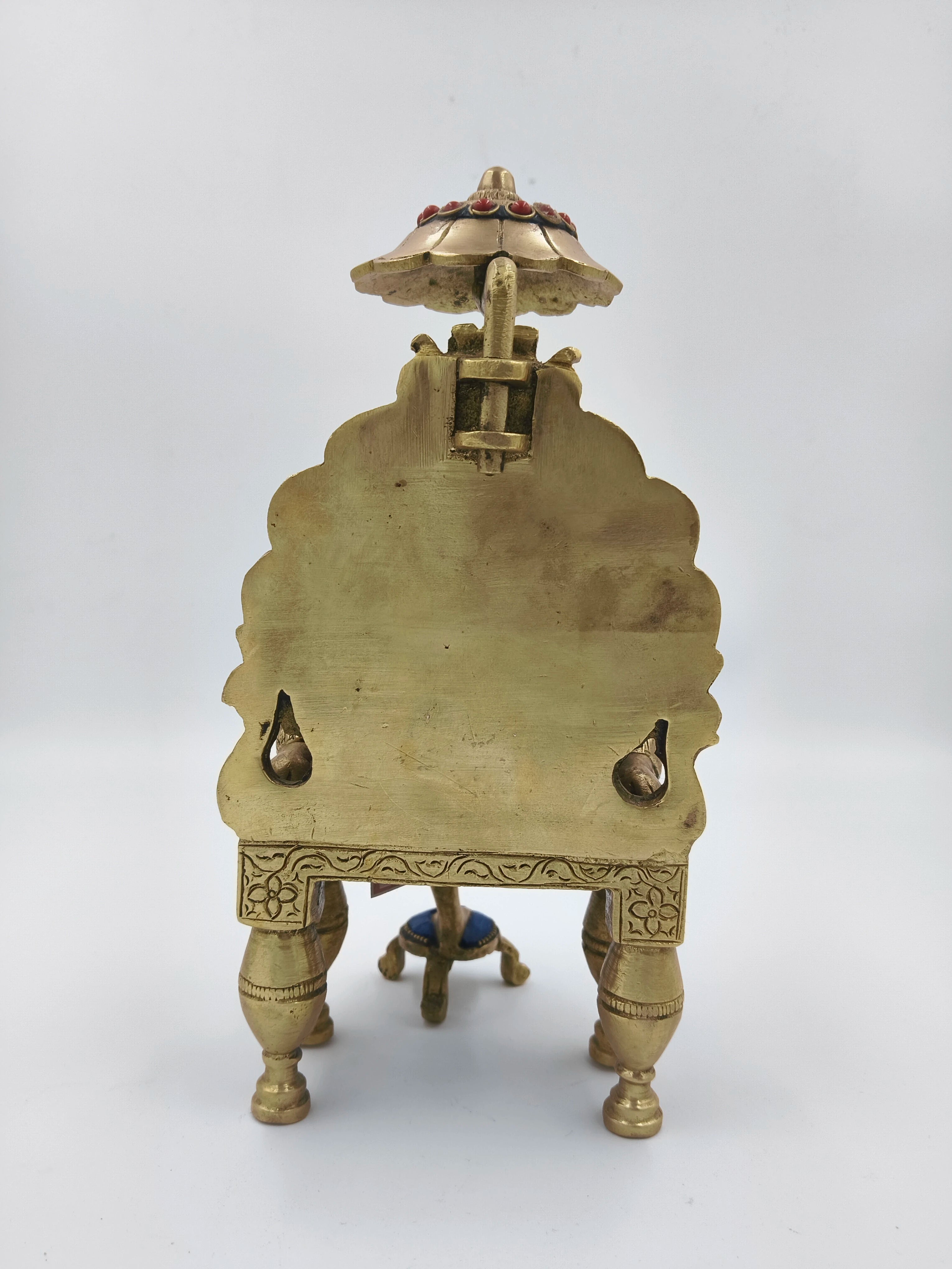 Back view of brass Shirdi Sai Baba figurine seated on decorated simhasan throne