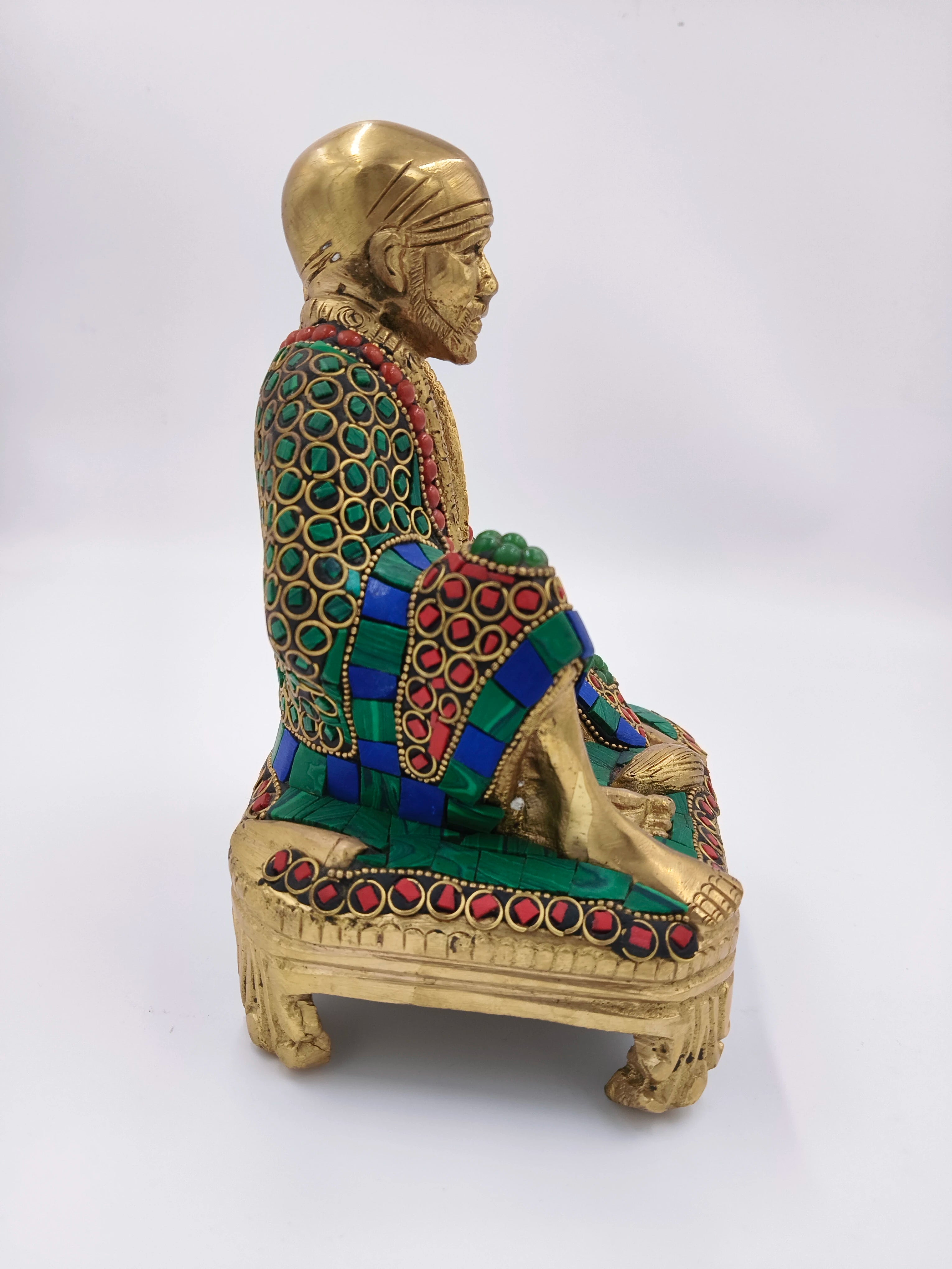 Side view of large brass Shirdi Sai Baba statue seated on decorated chowki