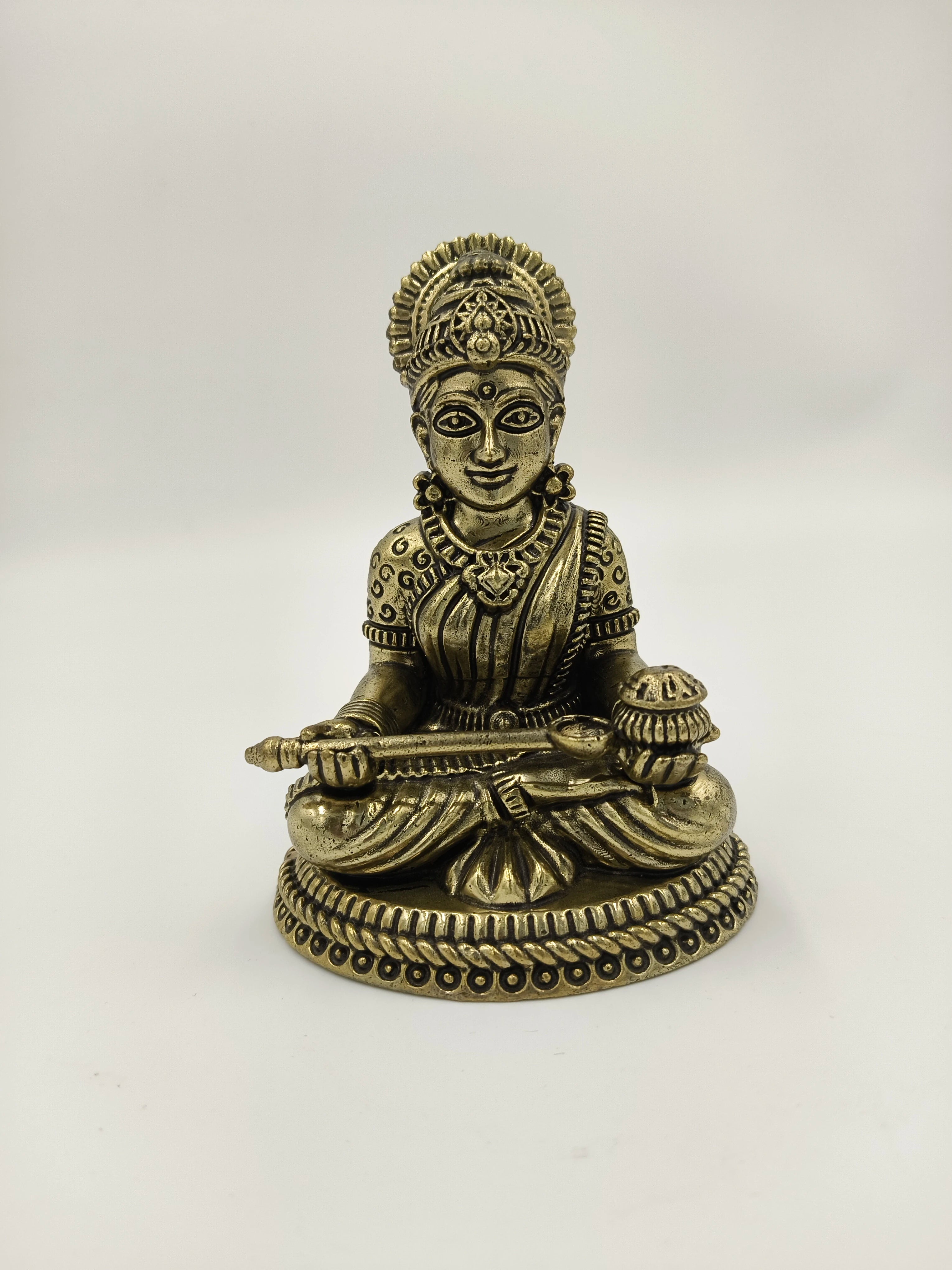 Small brass sculpture of seated Annapoorna goddess holding a ladle and bowl
