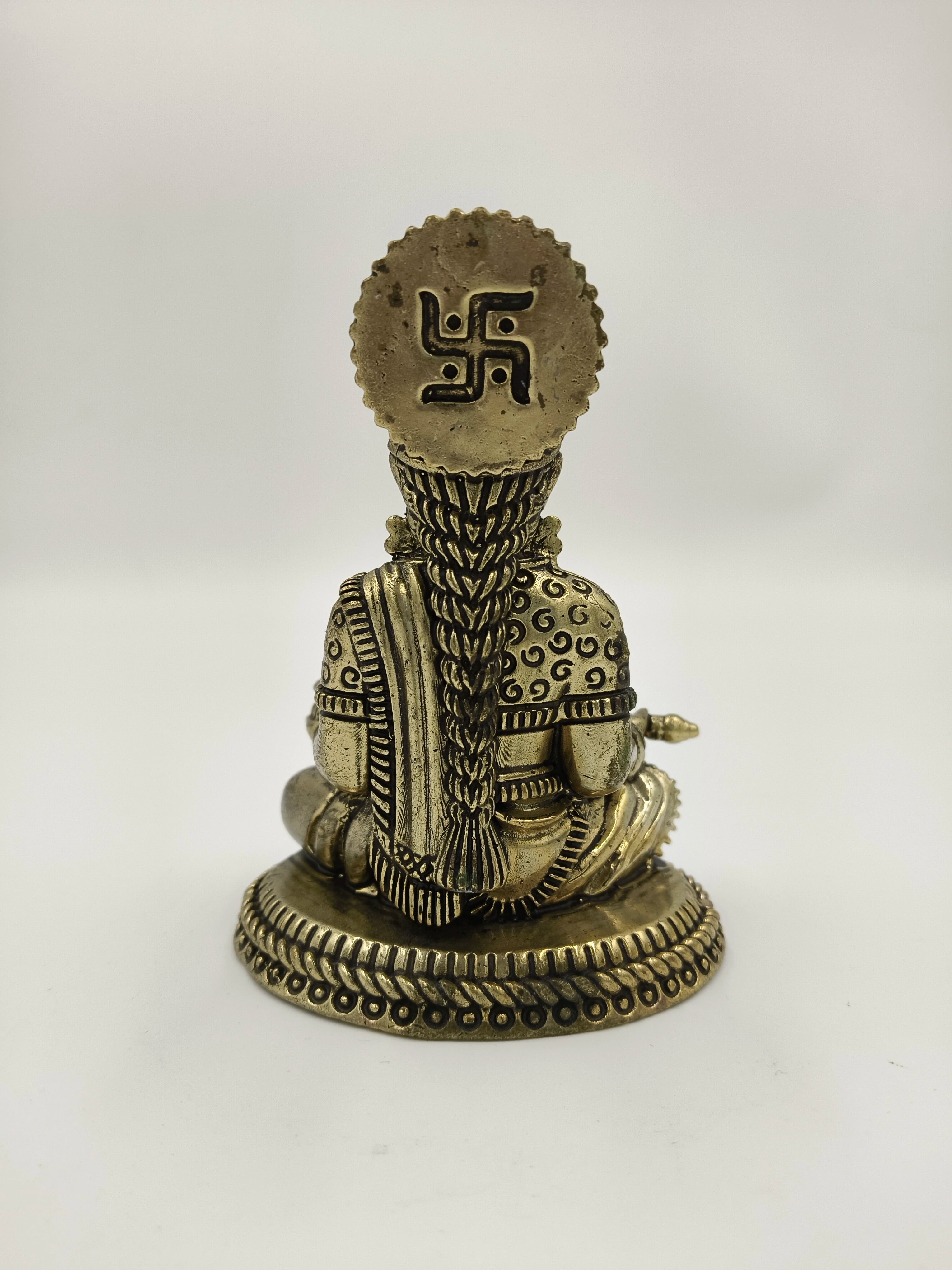 Back view of small brass Annapoorna sculpture with intricate hair and Swastika symbol