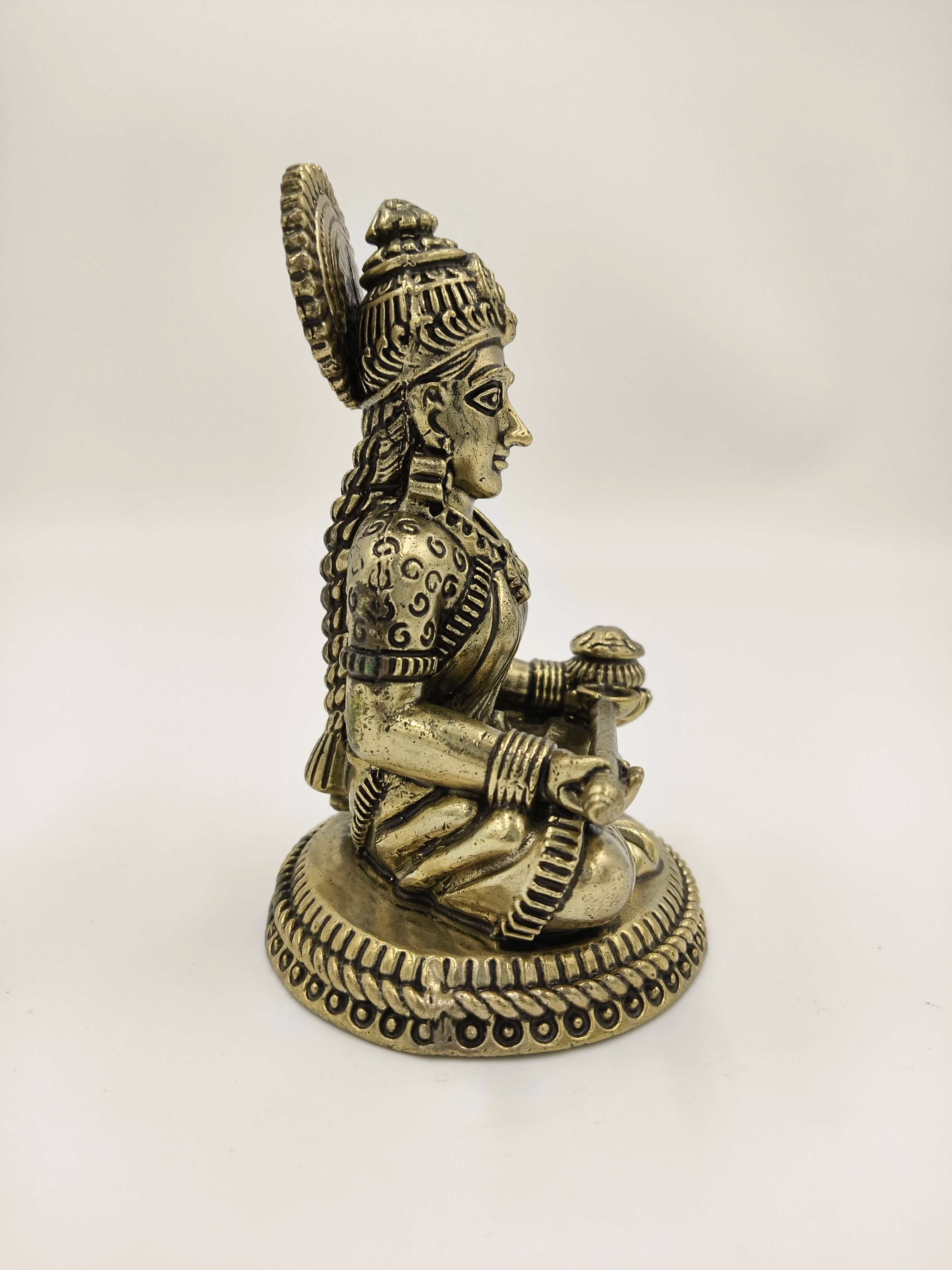 Brass Annapoorna statue seated on a decorative base, side view
