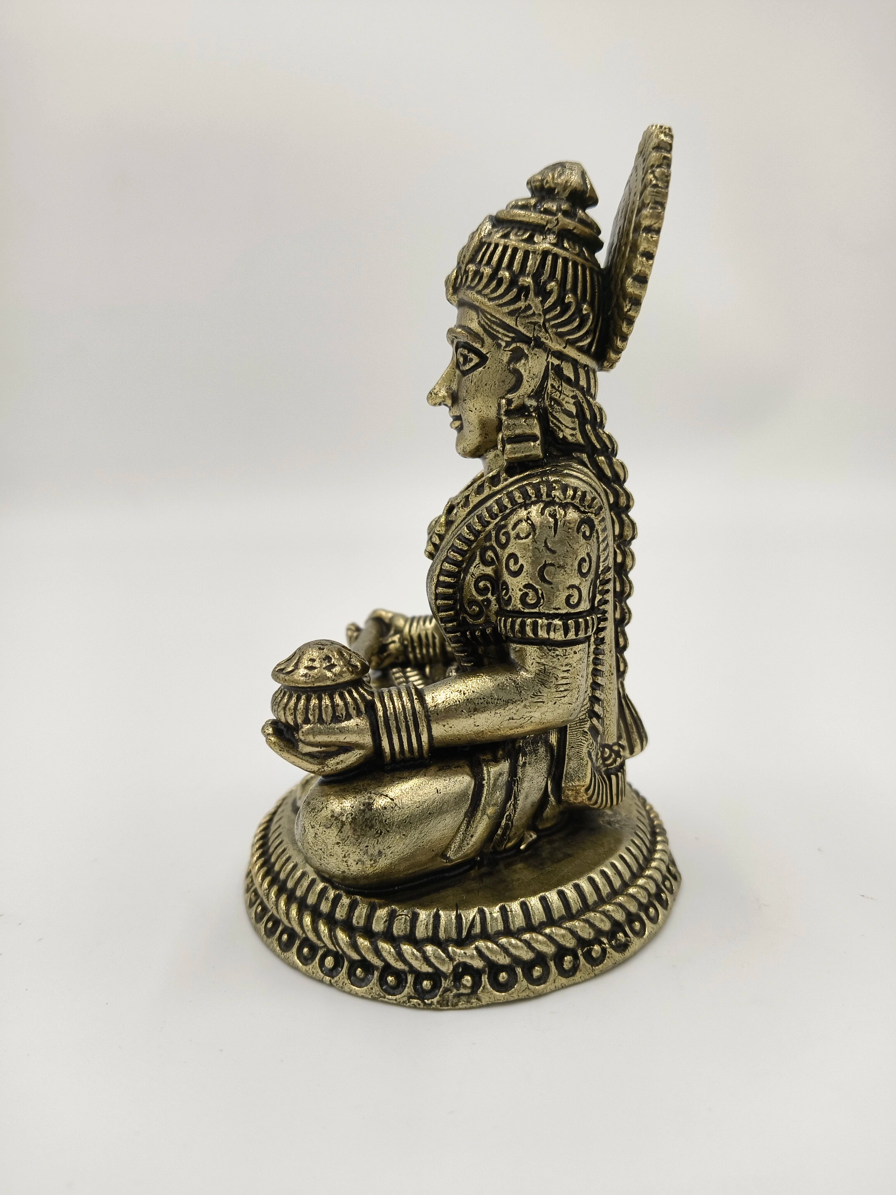 Side view of small brass Annapoorna deity sculpture seated on decorated base