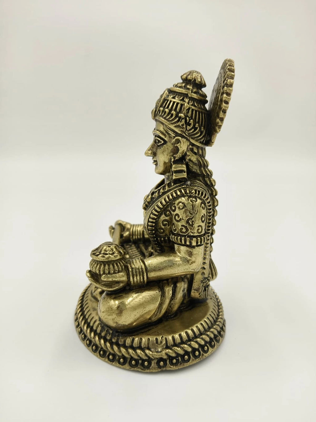 Side view brass statue of Annapoorna goddess seated on ornate base