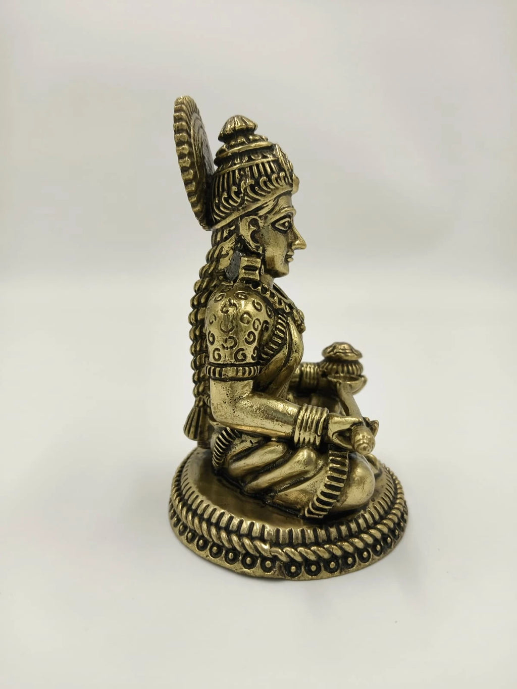 Side view of small brass Annapoorna sitting statue with detailed base