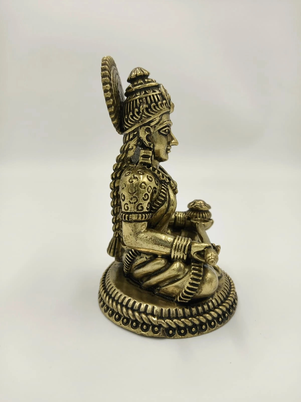 Side view of small brass Annapoorna sitting statue with detailed base