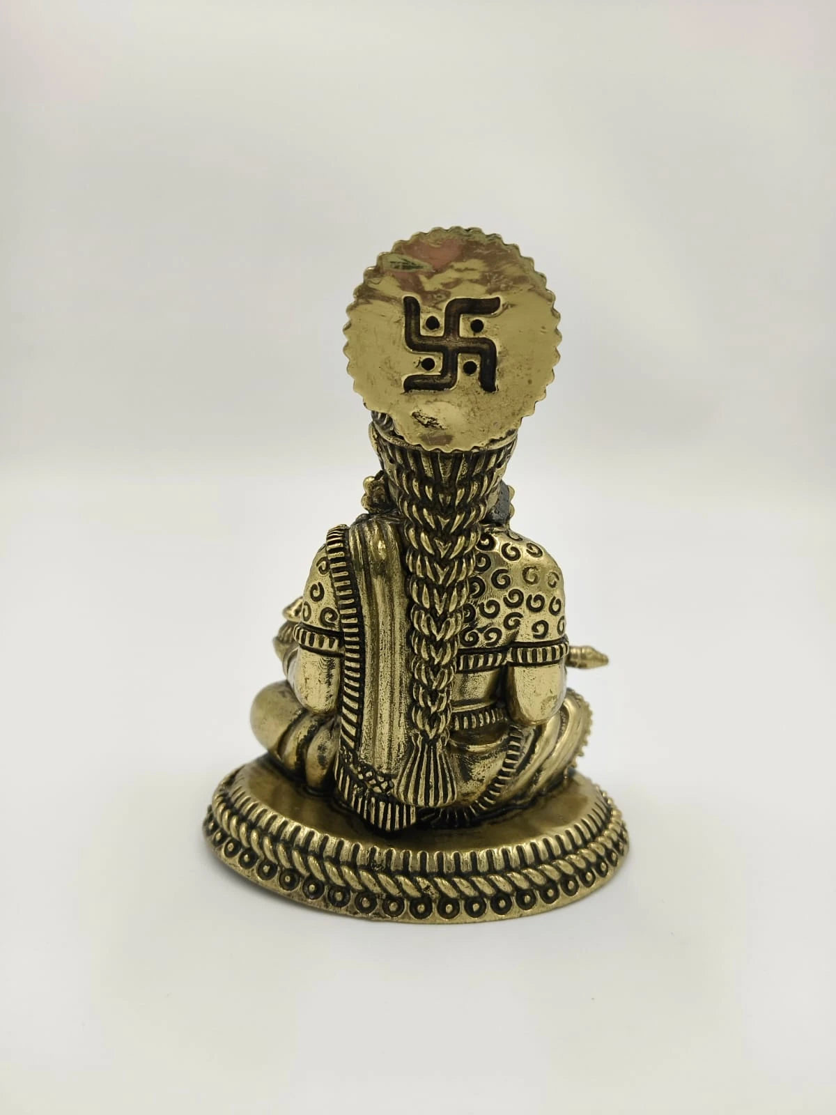Small brass Annapoorna sculpture showing the detailed back side with braided hair and decorative base