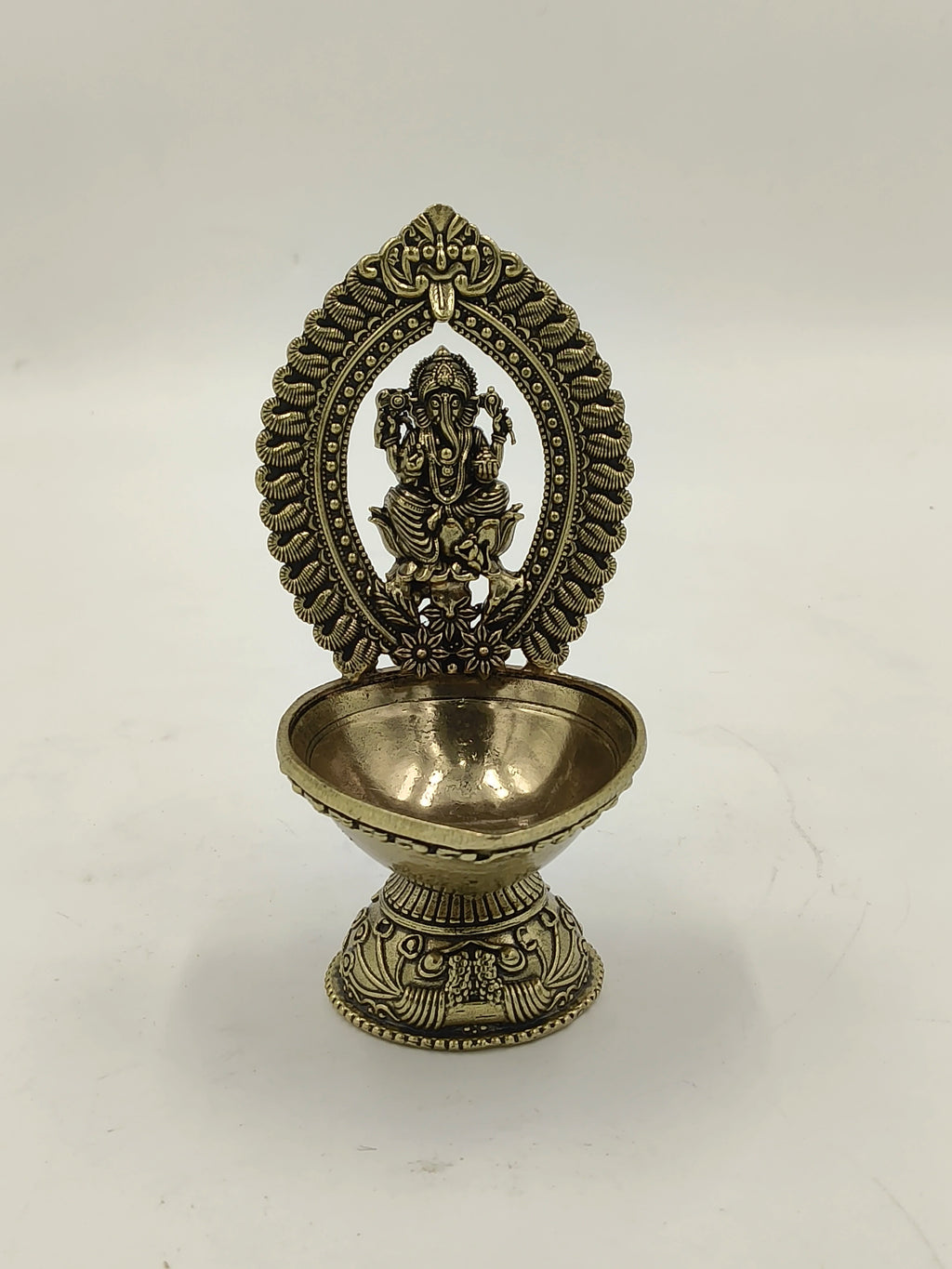Medium brass sculpture of Lord Ganesha within decorative arch on pedestal bowl