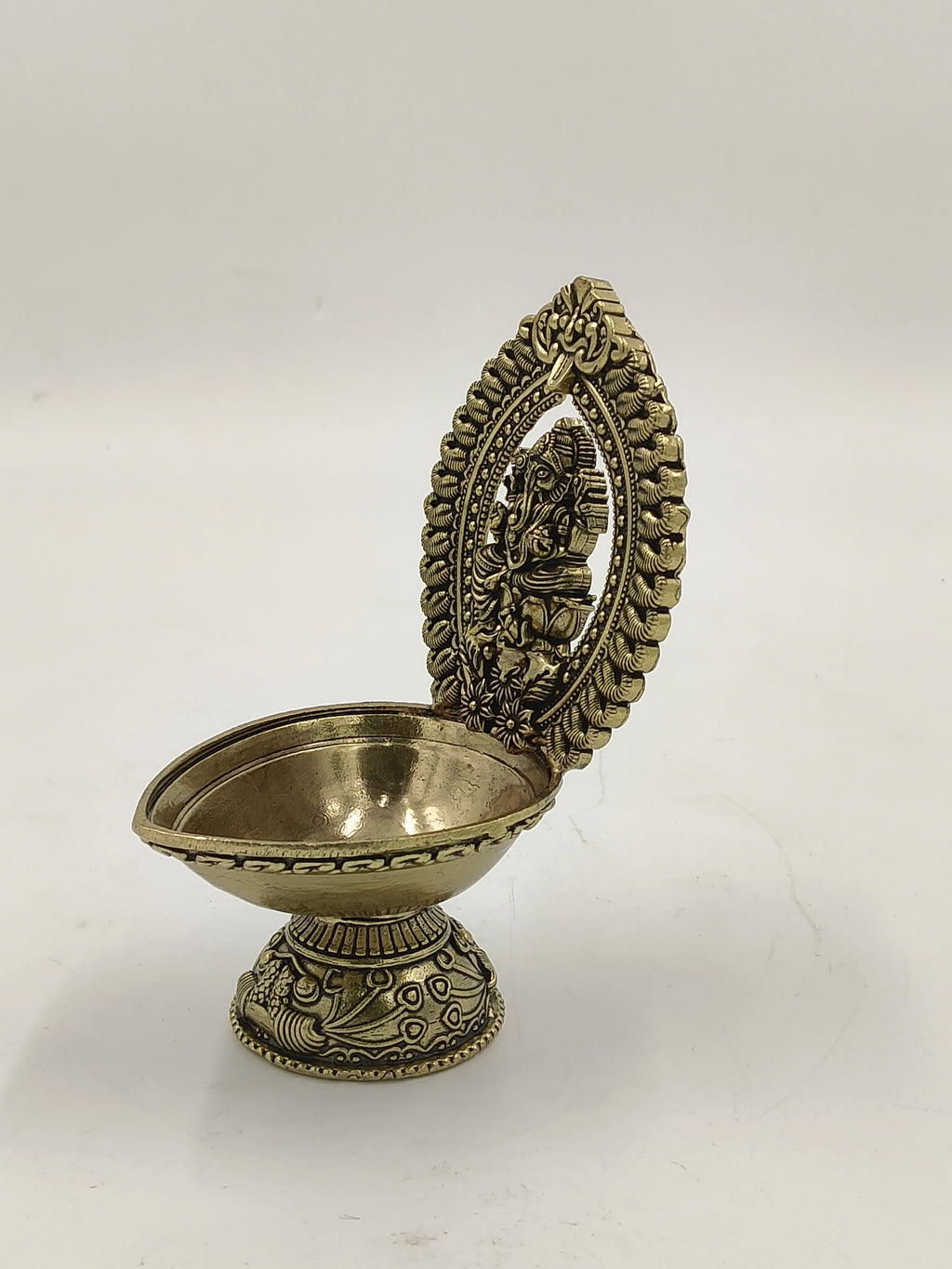 Brass oil lamp with detailed arch featuring seated Ganesh sculpture