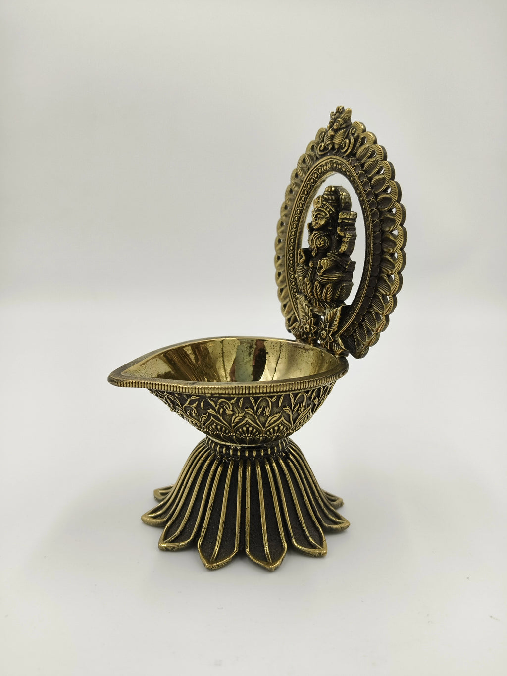 Brass diya lamp with Lakshmi deity sculpture and decorative arch