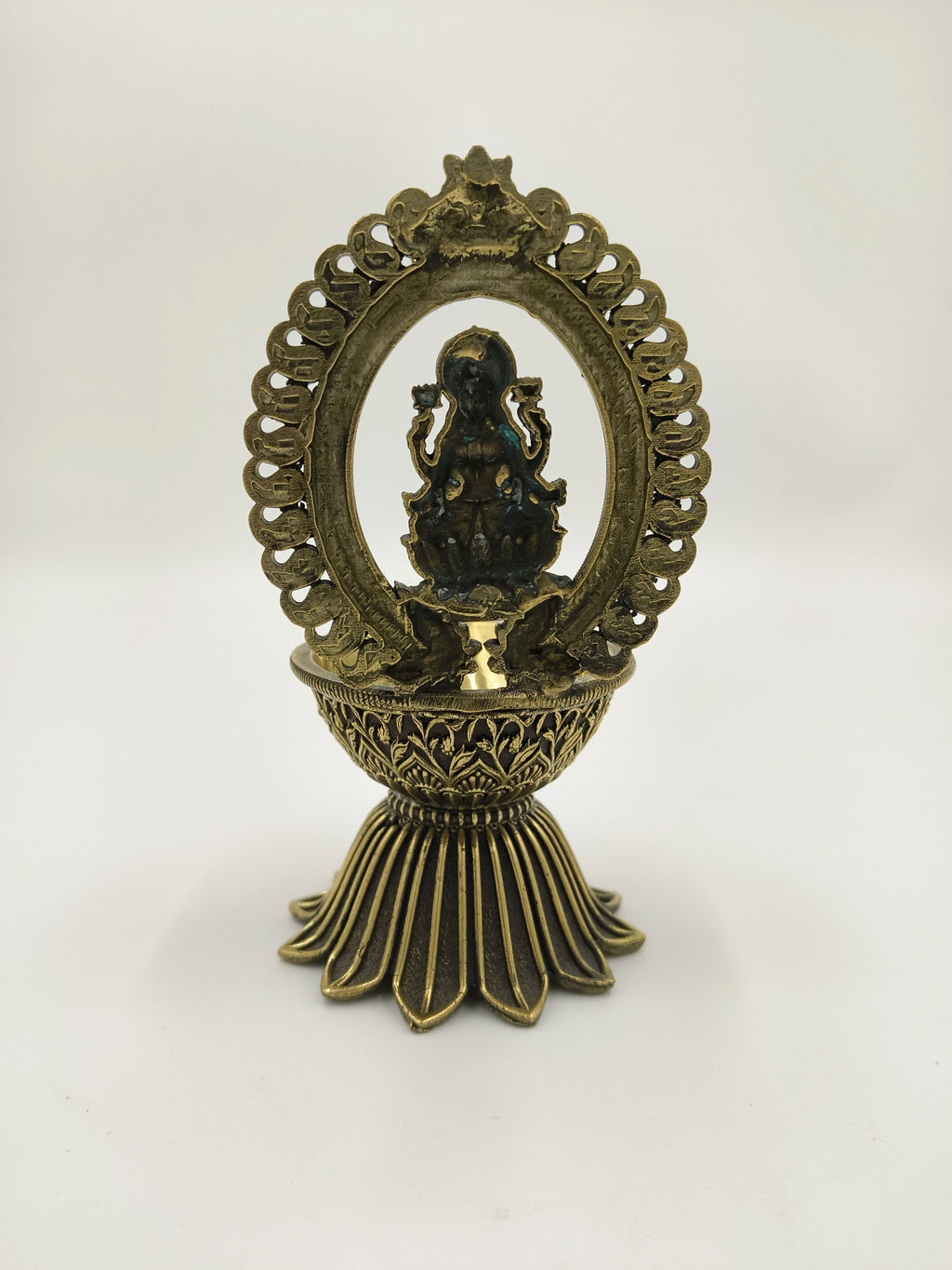 Large brass sculpture of Lakshmi under decorative arch on pedestal base
