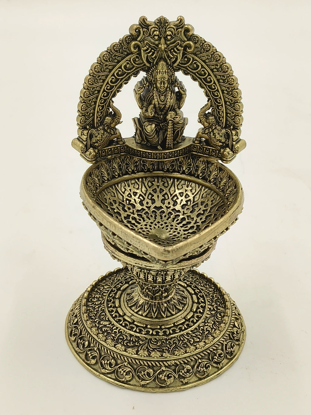 Intricately carved brass sculpture of goddess Lakshmi with decorative arch and bowl
