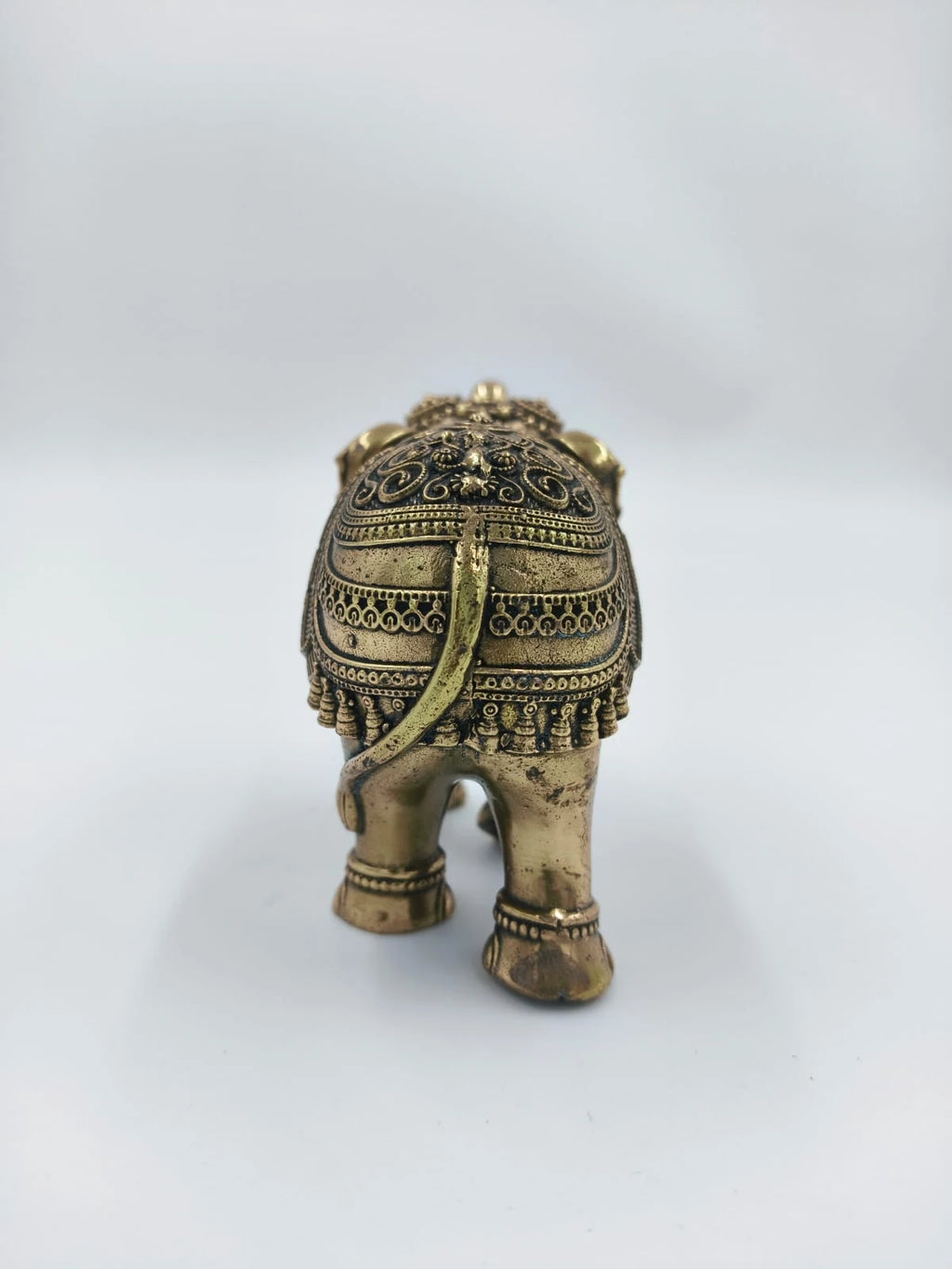 Rear view of small brass elephant figurine with intricate detailing