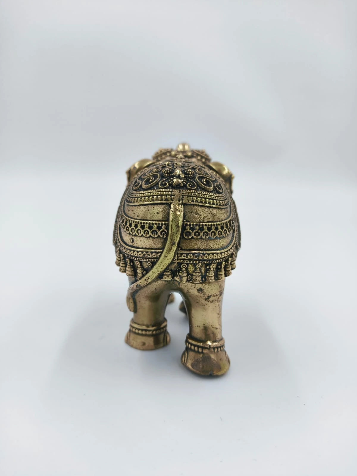 Rear view of small brass elephant figurine with intricate detailing