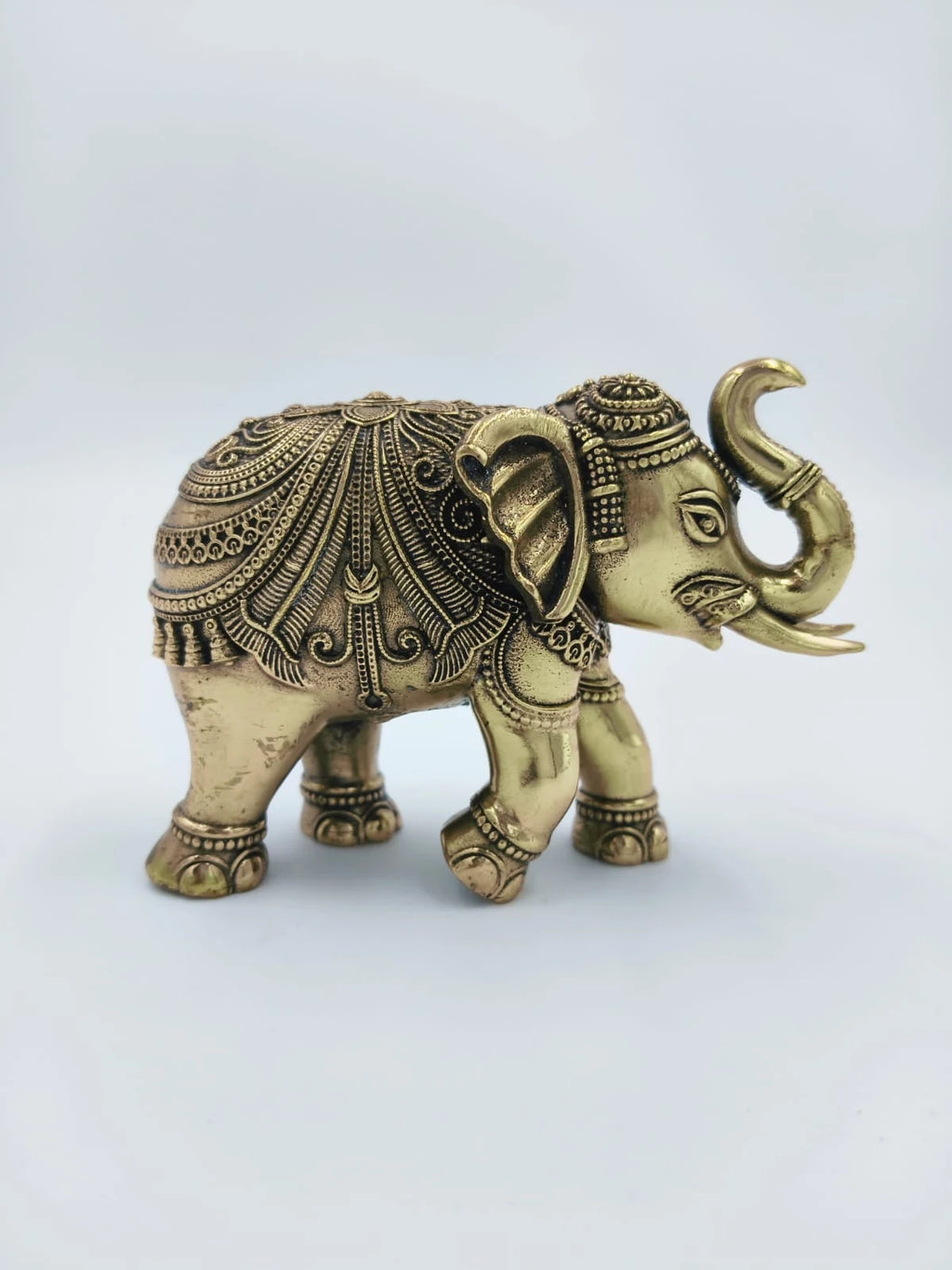 Small brass elephant figurine with detailed decorative patterns side view