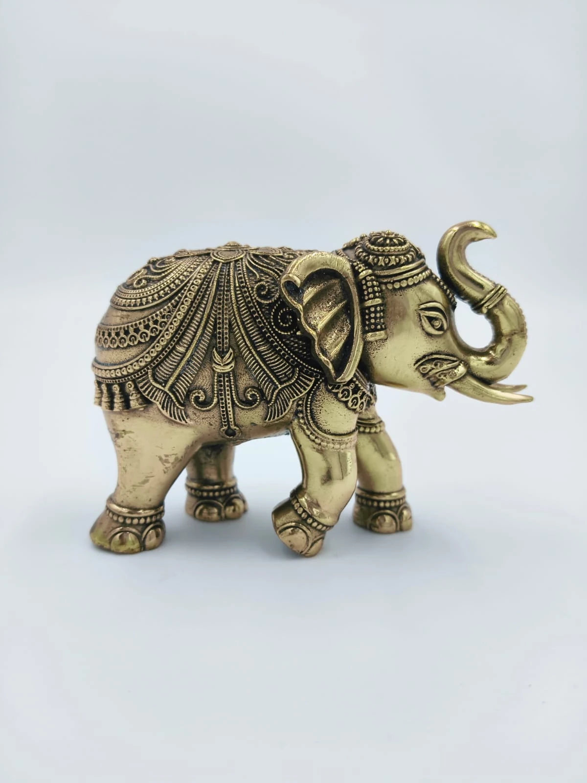Small brass elephant figurine with detailed decorative patterns side view