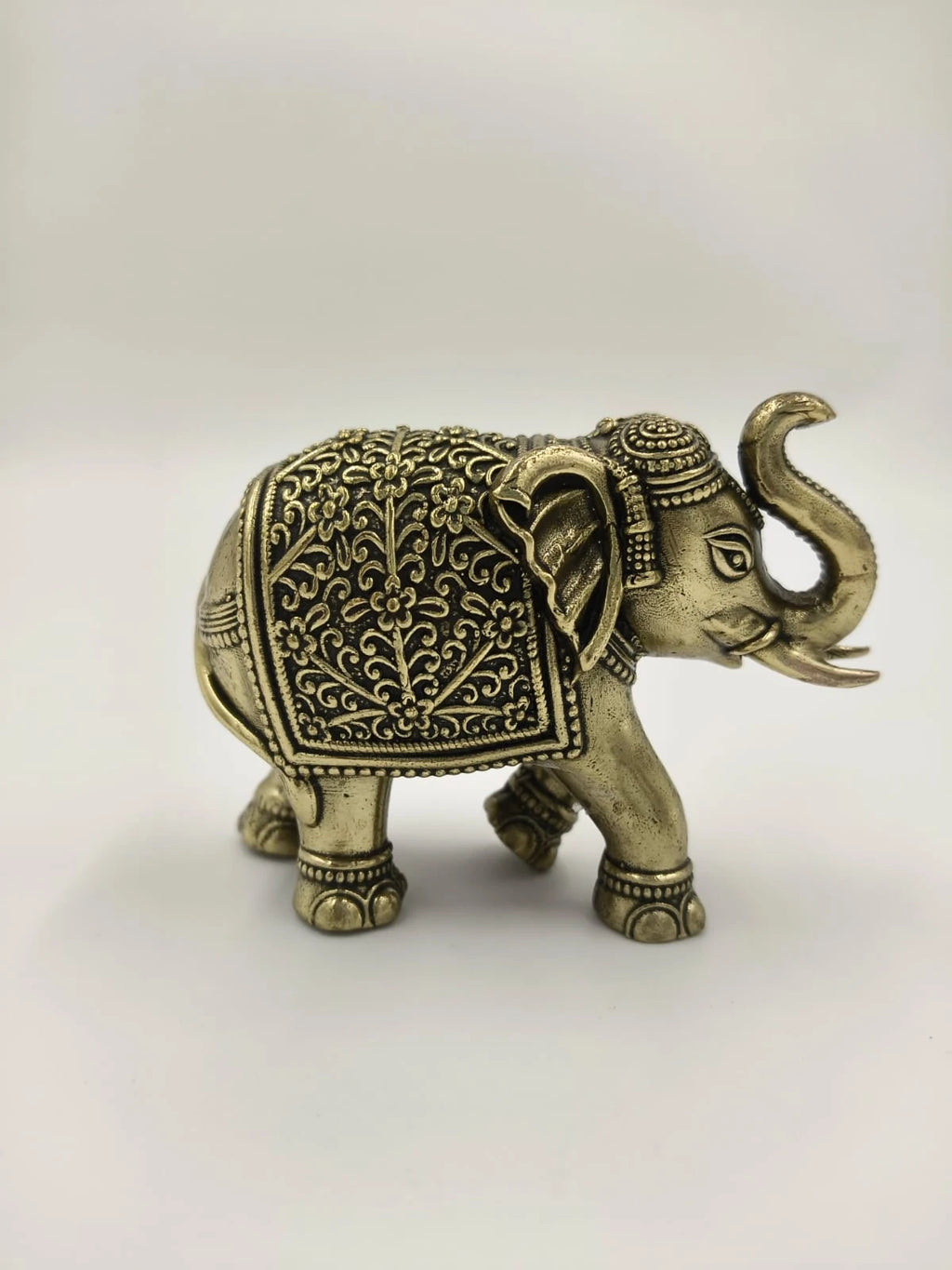 Mini brass elephant sculpture with intricate floral patterns side view