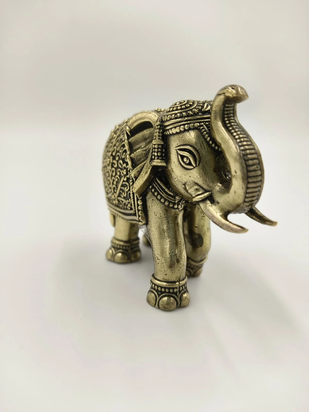 Mini brass elephant sculpture with detailed carvings and raised trunk