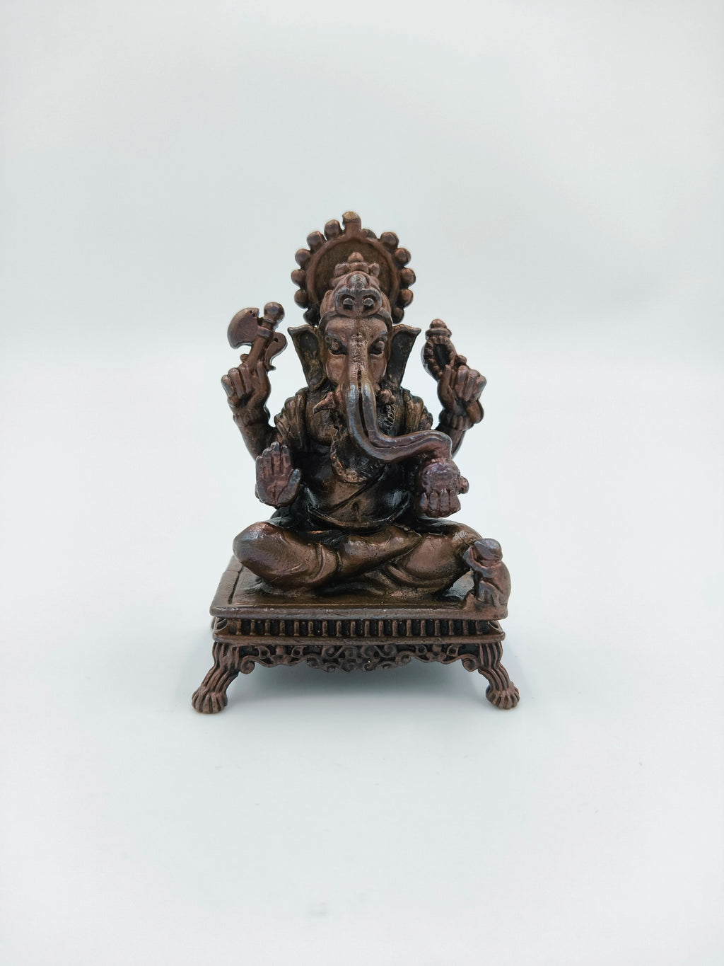 Mini copper Ganesh statue seated on a decorative chowki base