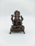 Mini copper Ganesh statue seated on a decorative chowki base