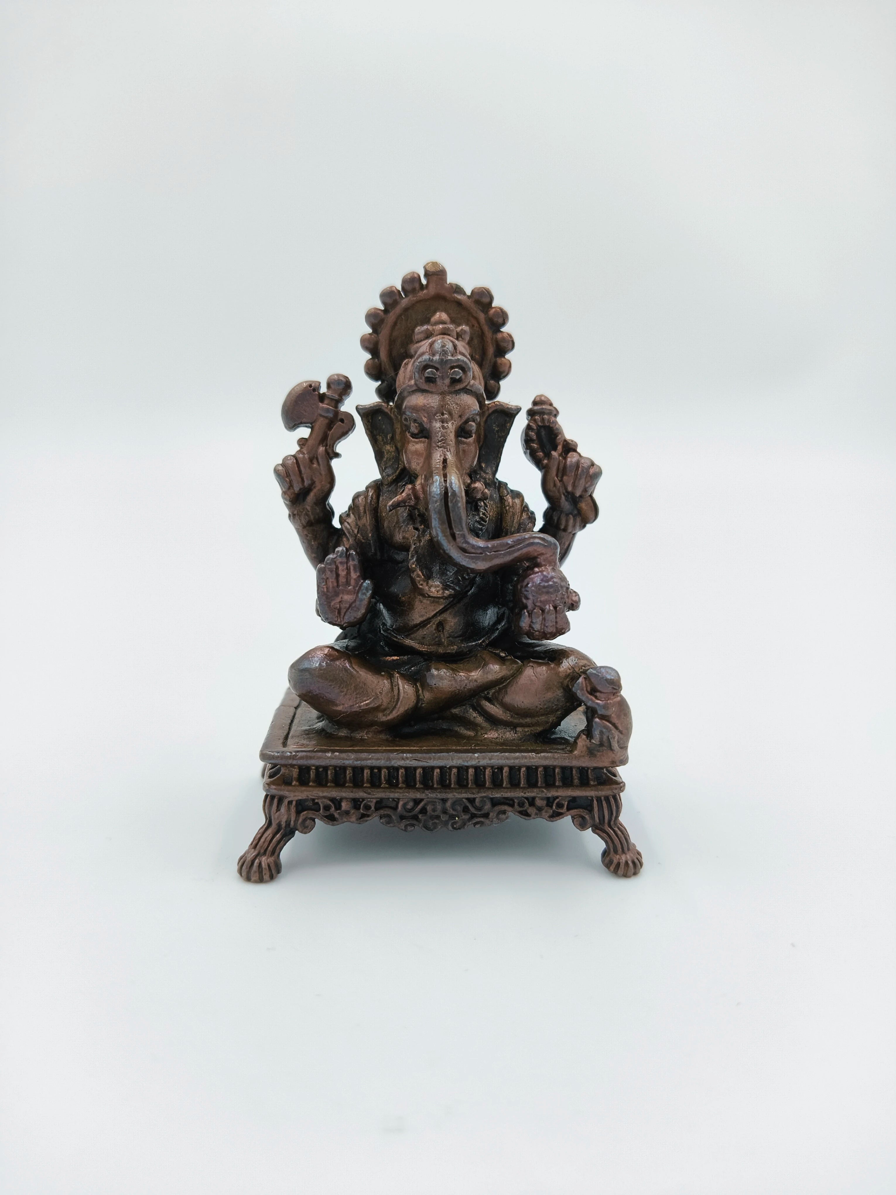 Mini copper Ganesh statue seated on a decorative chowki base