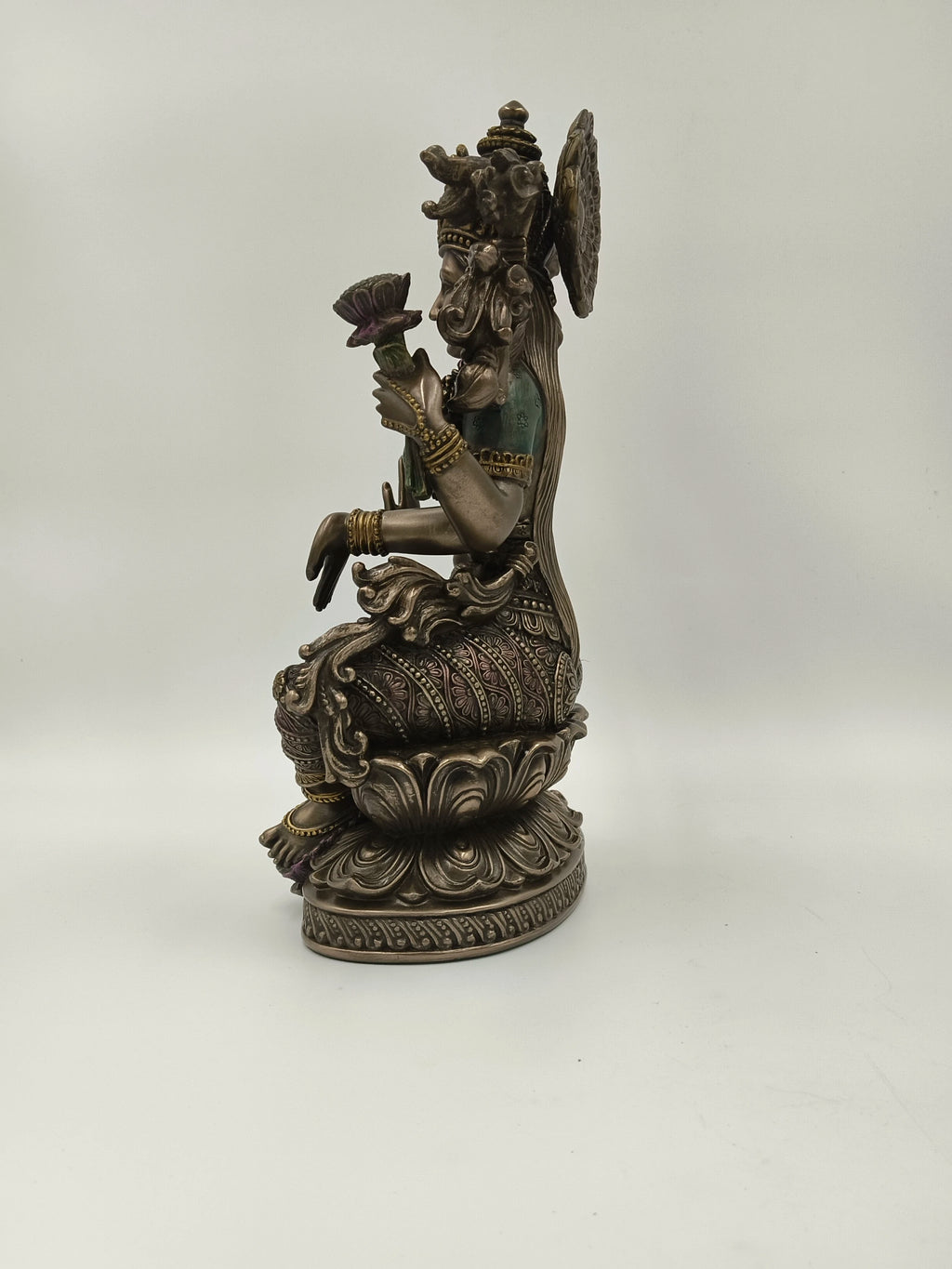 Side view of polyresin statue of Goddess Lakshmi seated on a lotus flower
