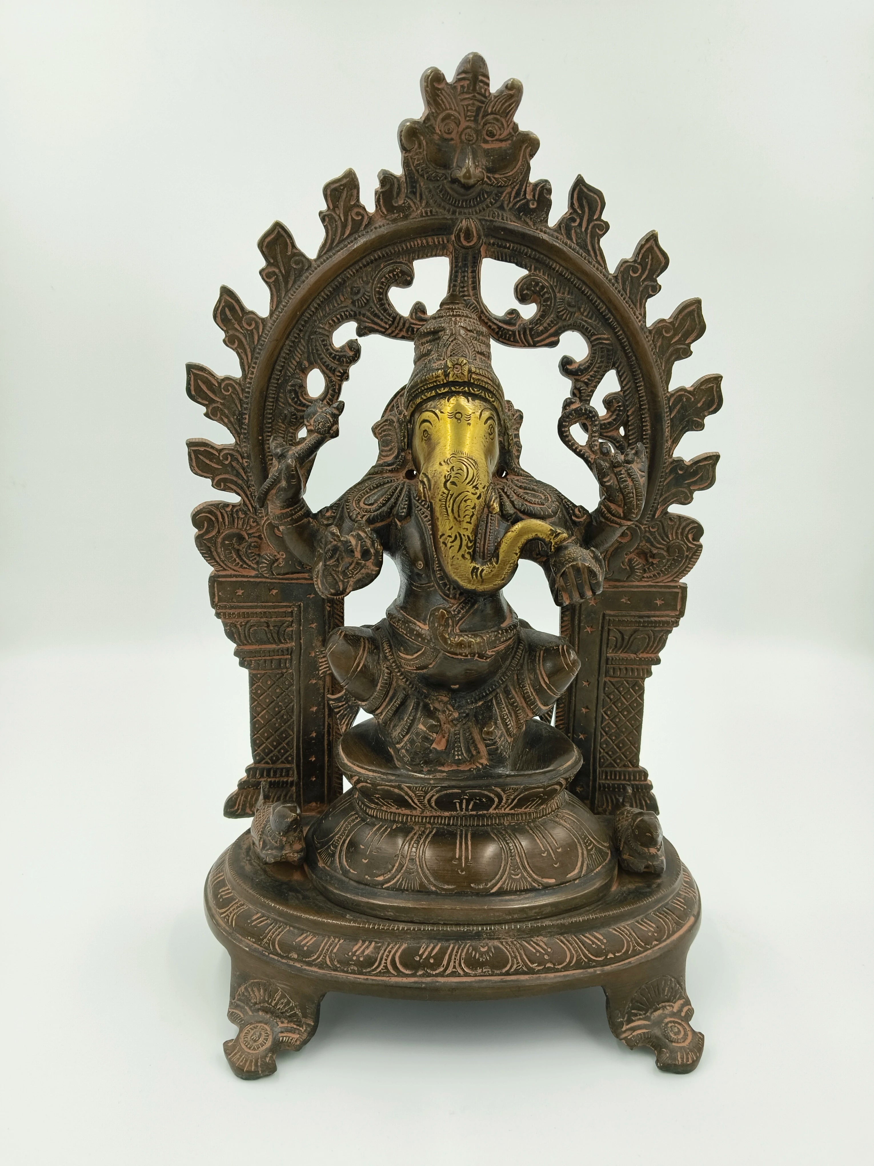 Large brass sculpture of Ganesh sitting under decorative arch