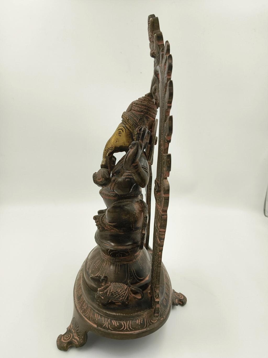 Side view of large brass Ganesh sculpture with decorative arch and mouse