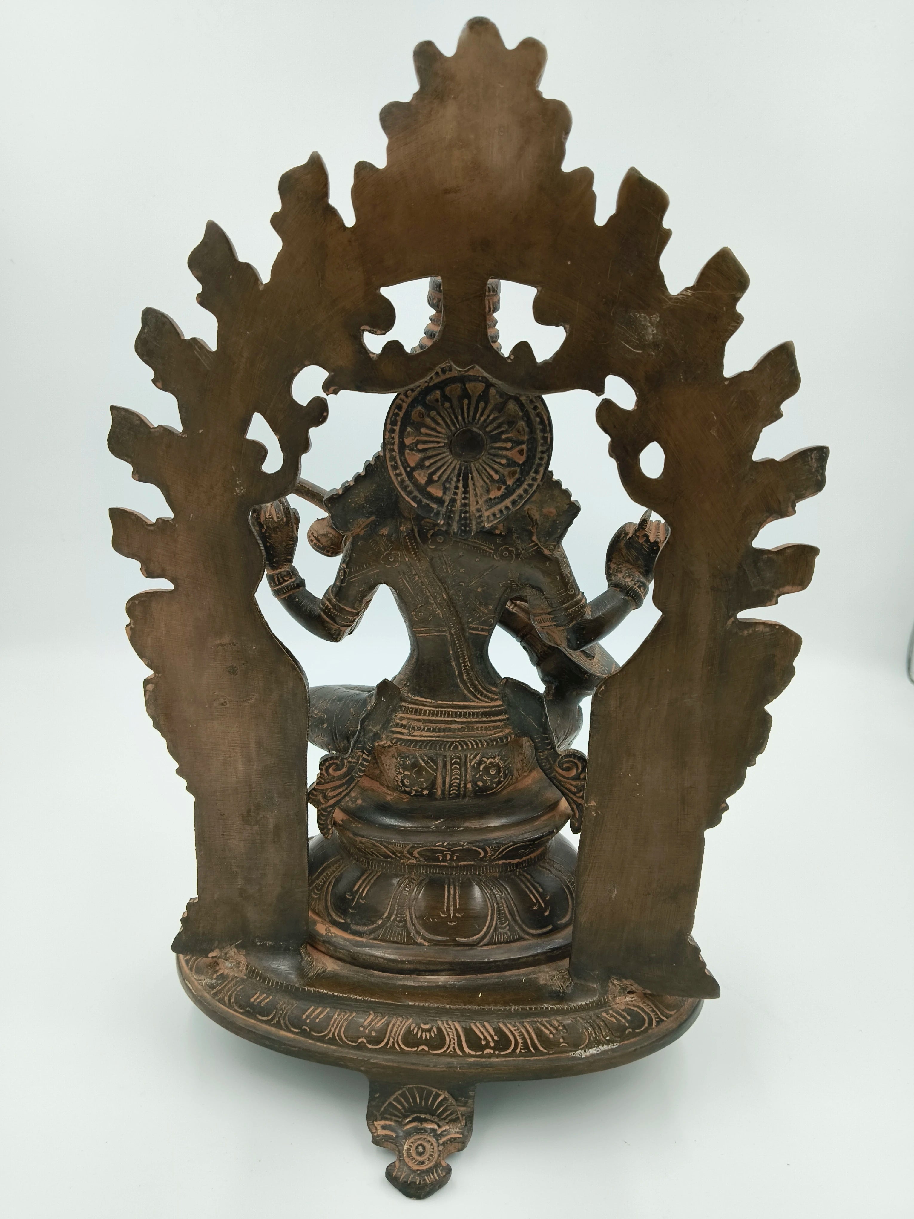 Back view of large brass Saraswathi statue with decorative arch