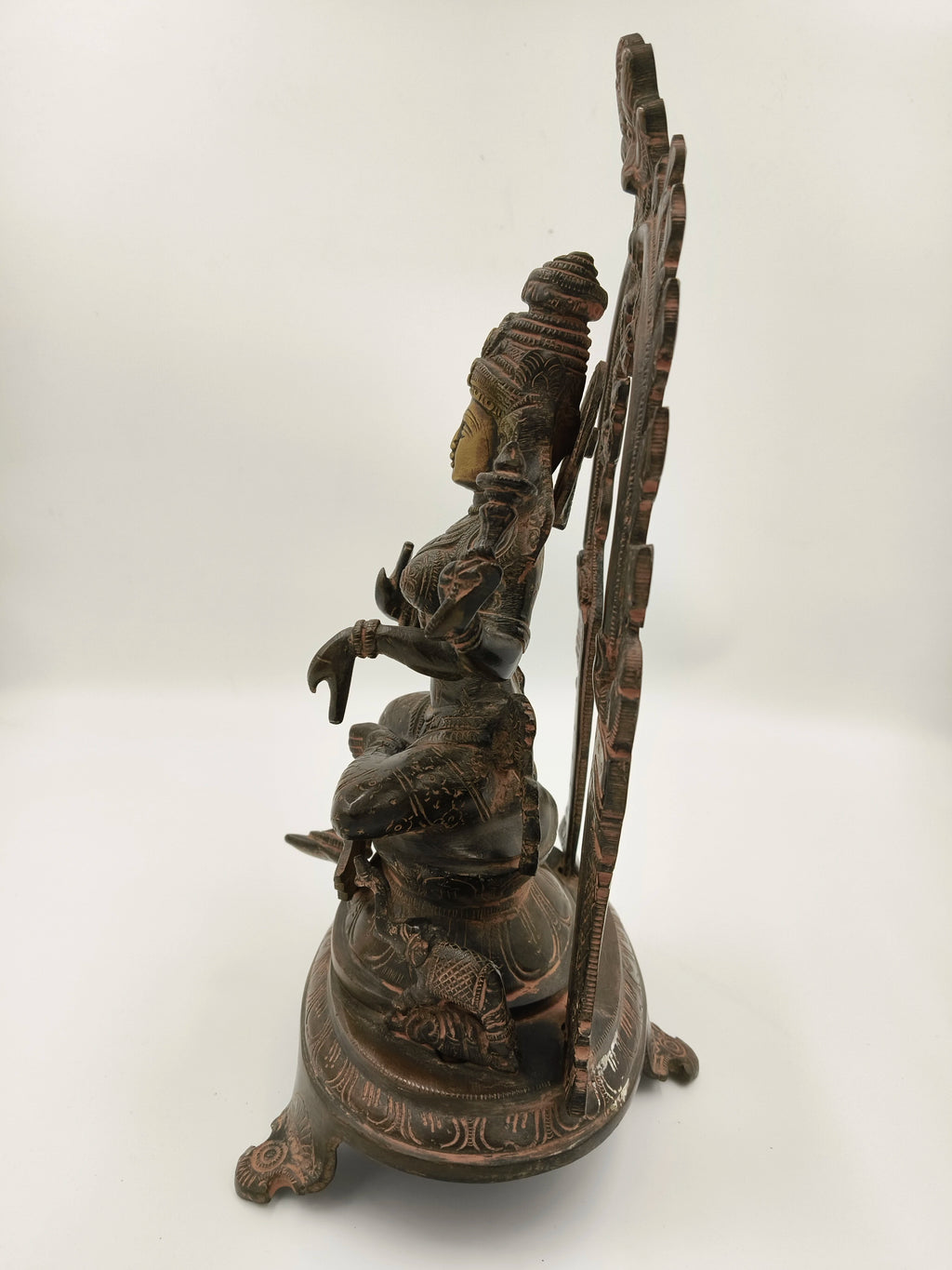 Side view of brass Lakshmi sculpture with ornate arch and detailed carvings