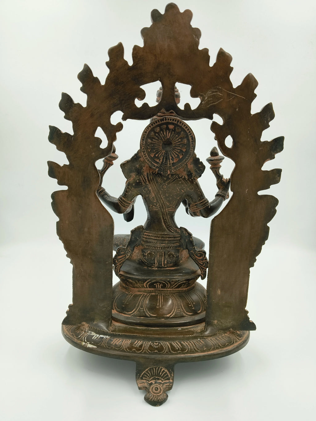 Back view of large brass Lakshmi statue with detailed arch and ornate base