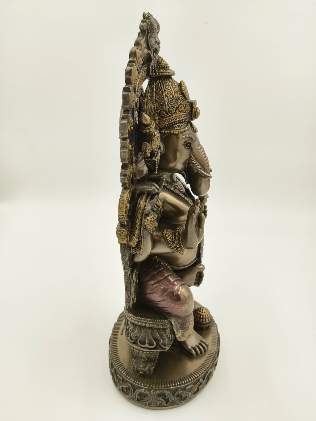 Side view of large polyresin Ganesh sculpture seated on decorated throne