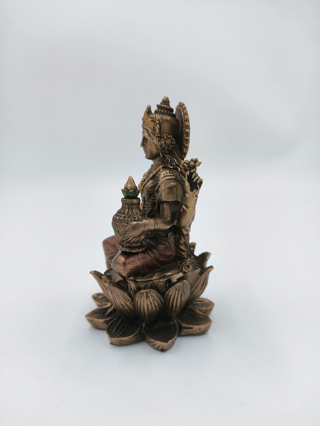Side view of small polyresin Lakshmi statue seated on lotus with Kalash