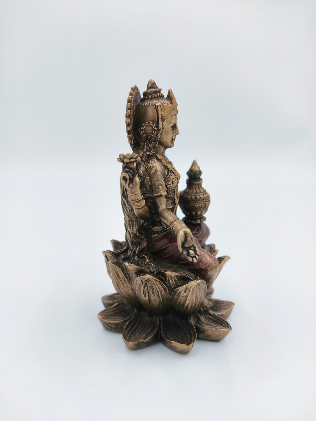Side view of small polyresin Lakshmi statue seated on lotus with Kalash