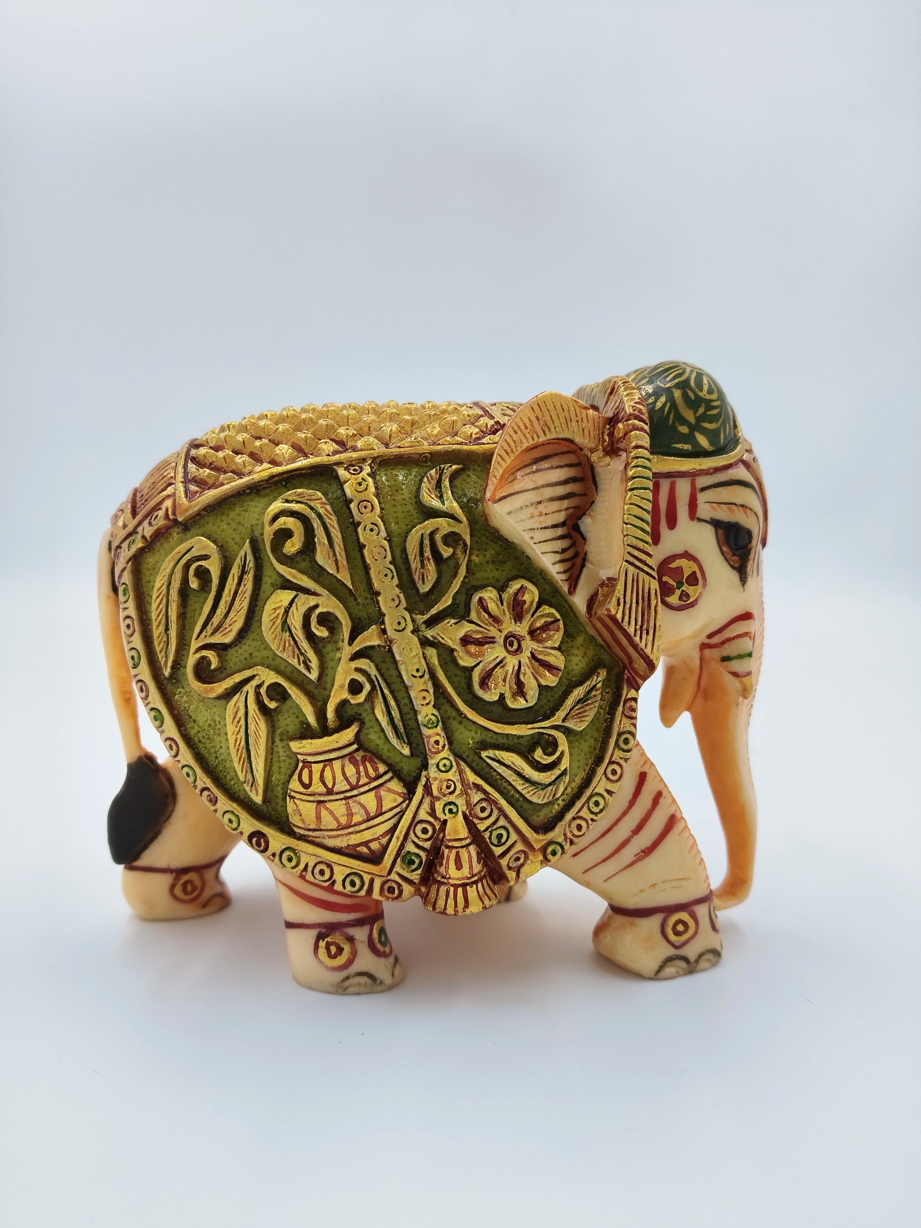 Small polyresin elephant figurine with intricate floral and leaf carvings side view