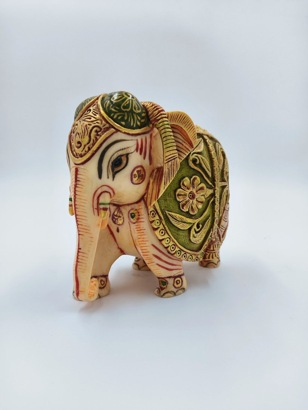 Small polyresin elephant figurine with detailed floral decorations side view