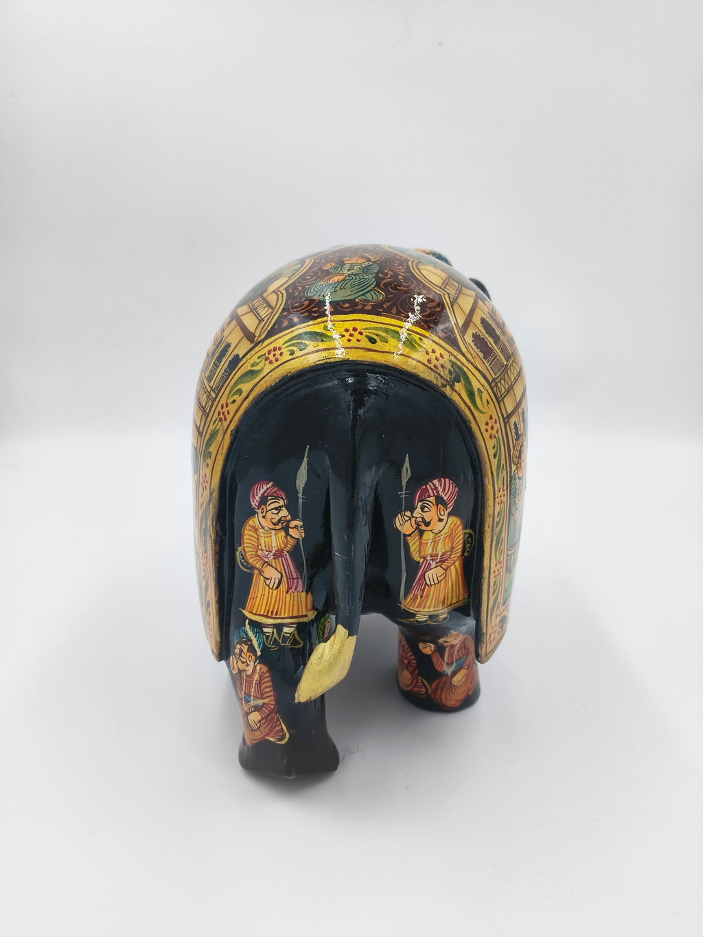 Rear view of painted wooden elephant sculpture with traditional figures and patterns