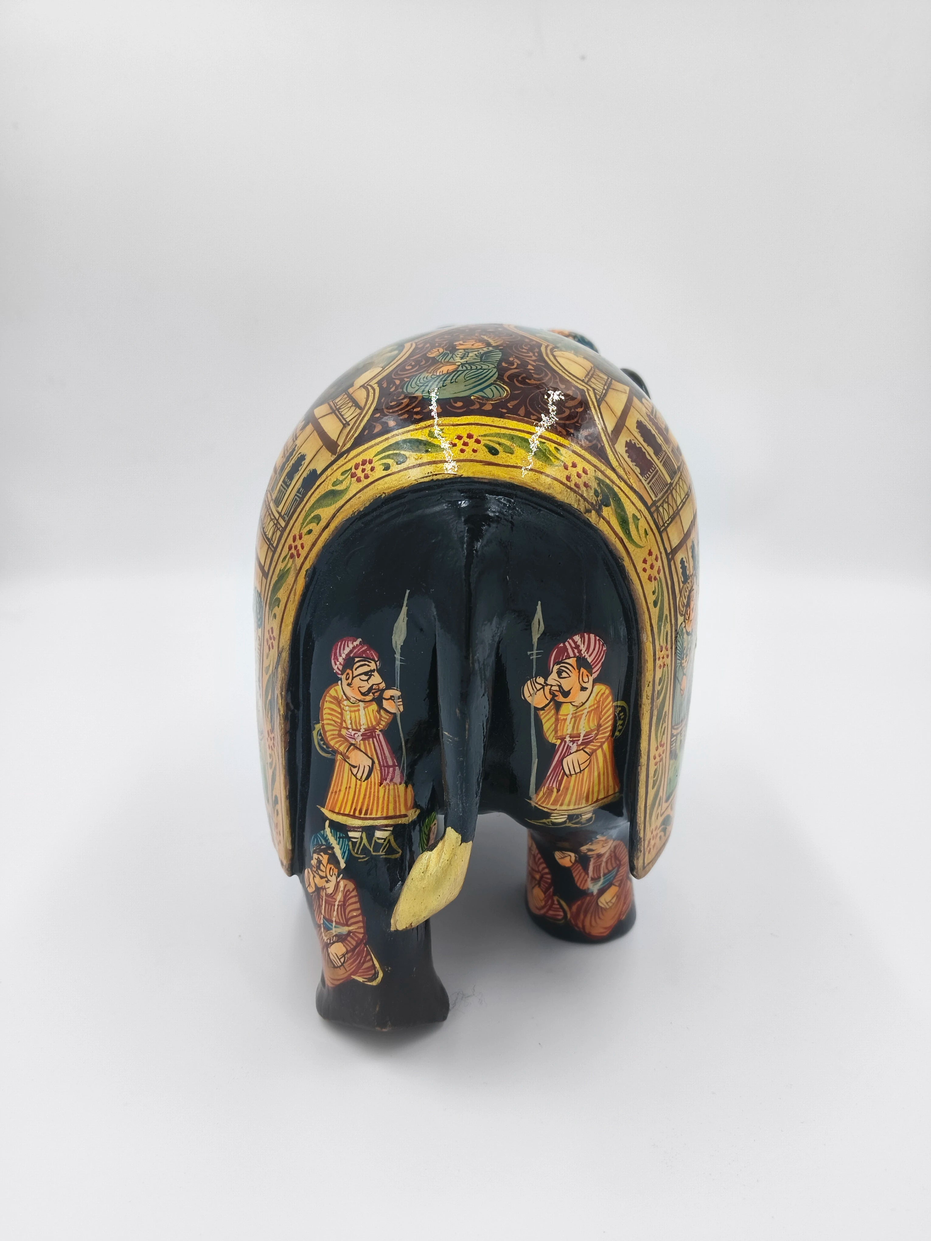 Rear view of painted wooden elephant sculpture with traditional figures and patterns