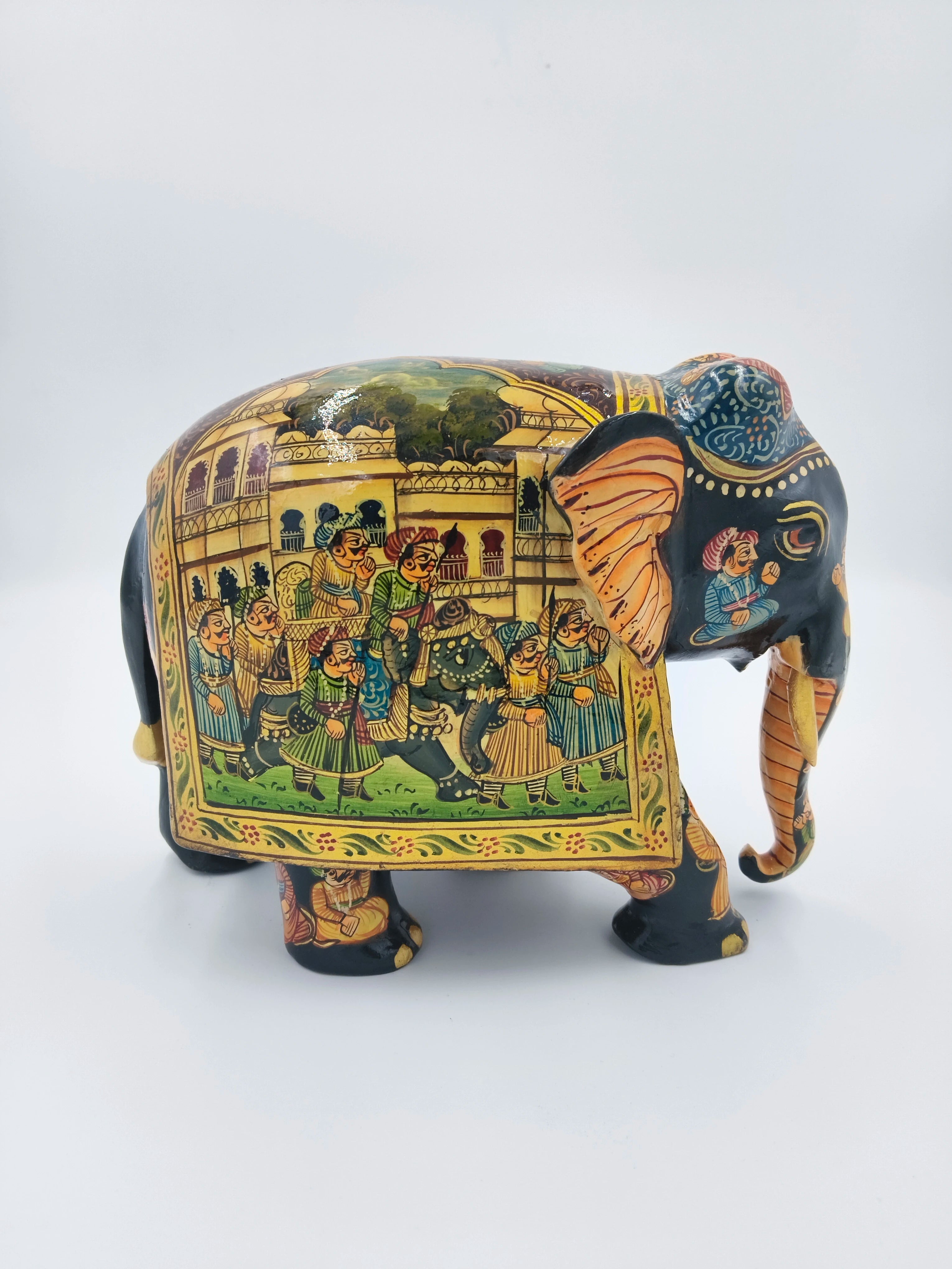 Wooden elephant sculpture with painted procession scene on side