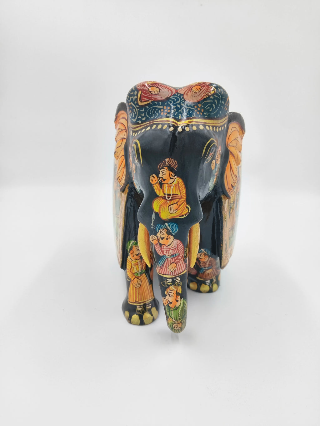 Front view of painted wooden elephant sculpture with procession figures