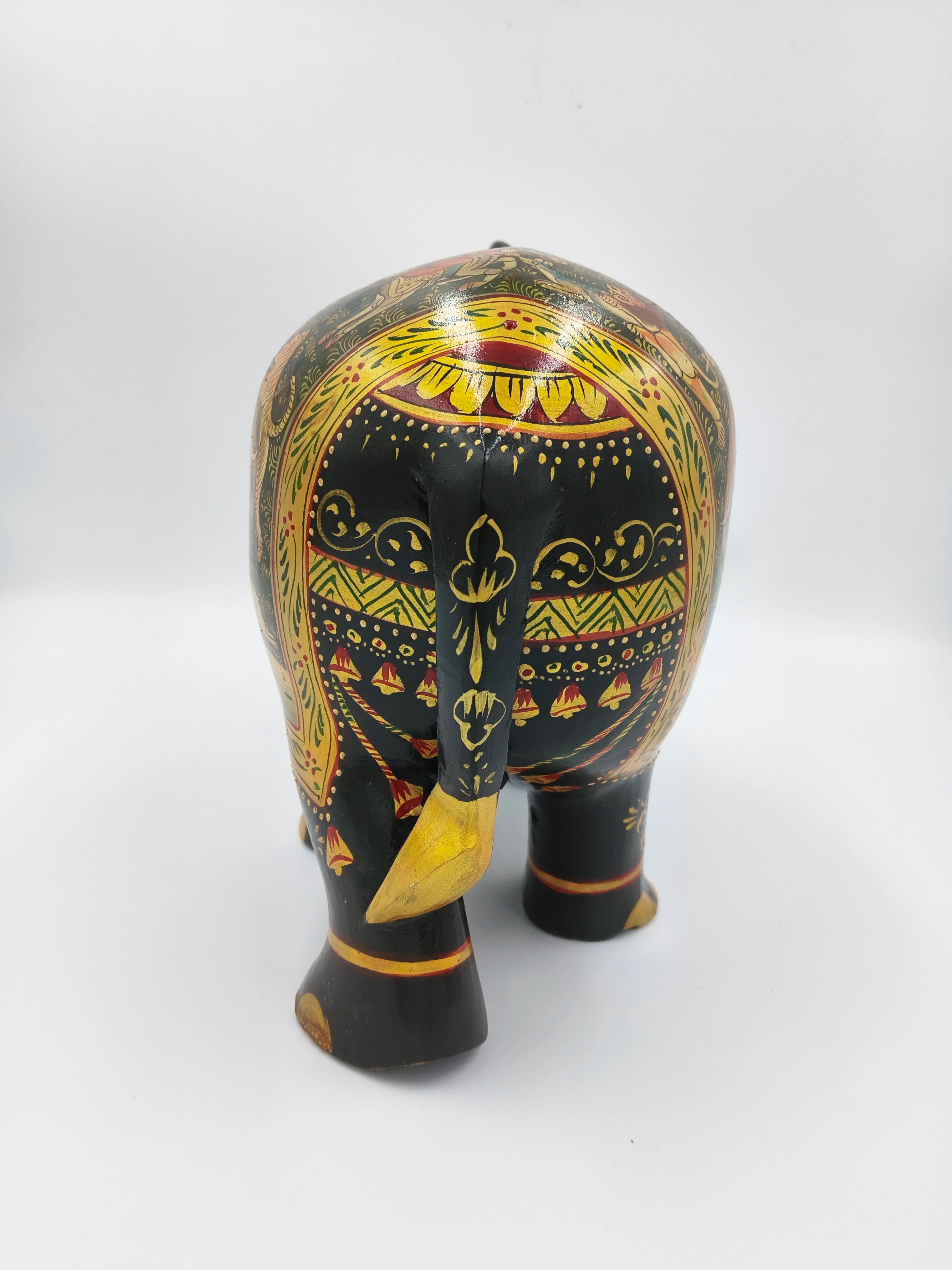 Back view of large wood elephant figurine painted with yellow and red decorative patterns