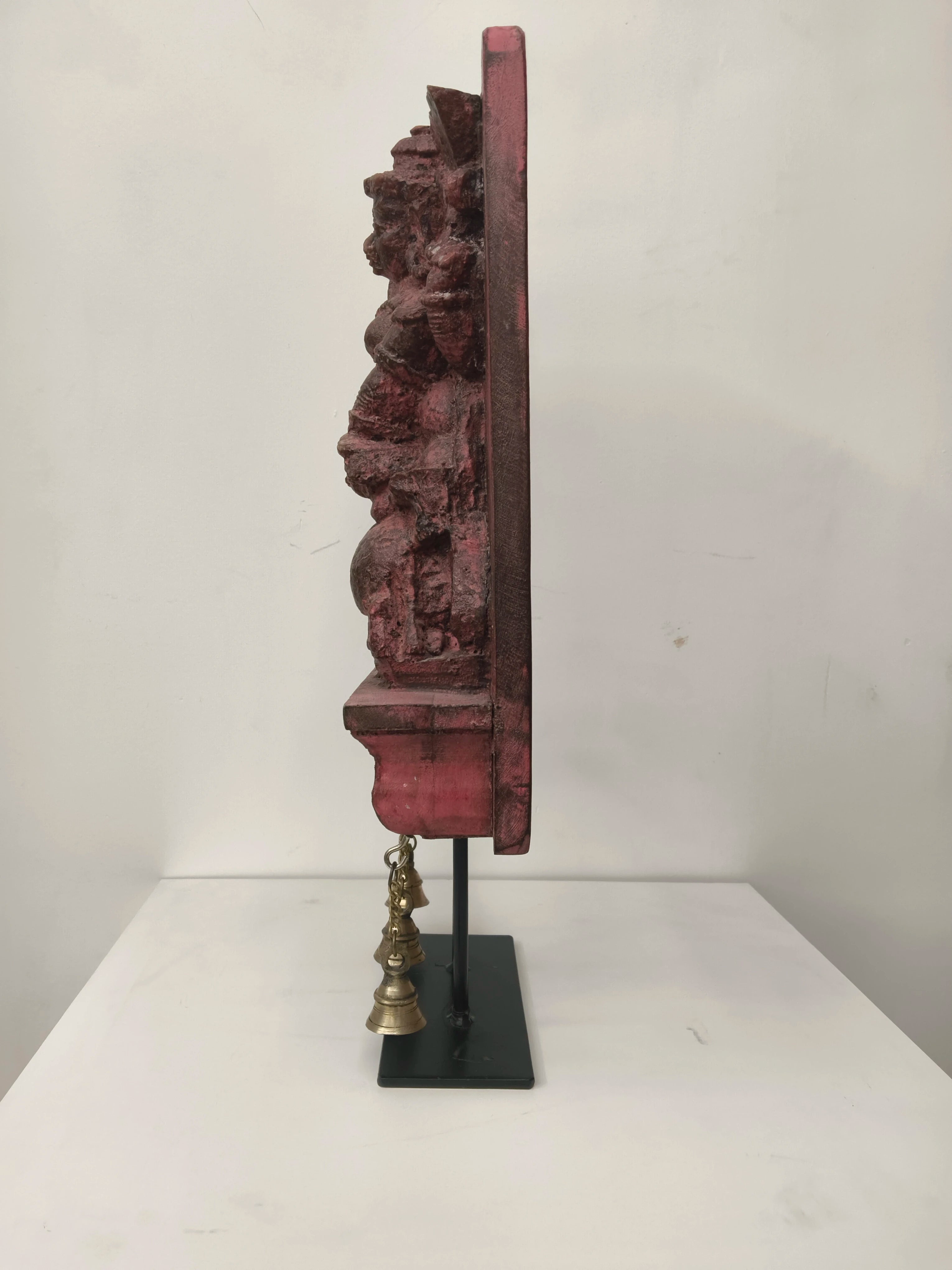 Side view of large wooden Mahishasura Mardini sculpture with hanging brass bells