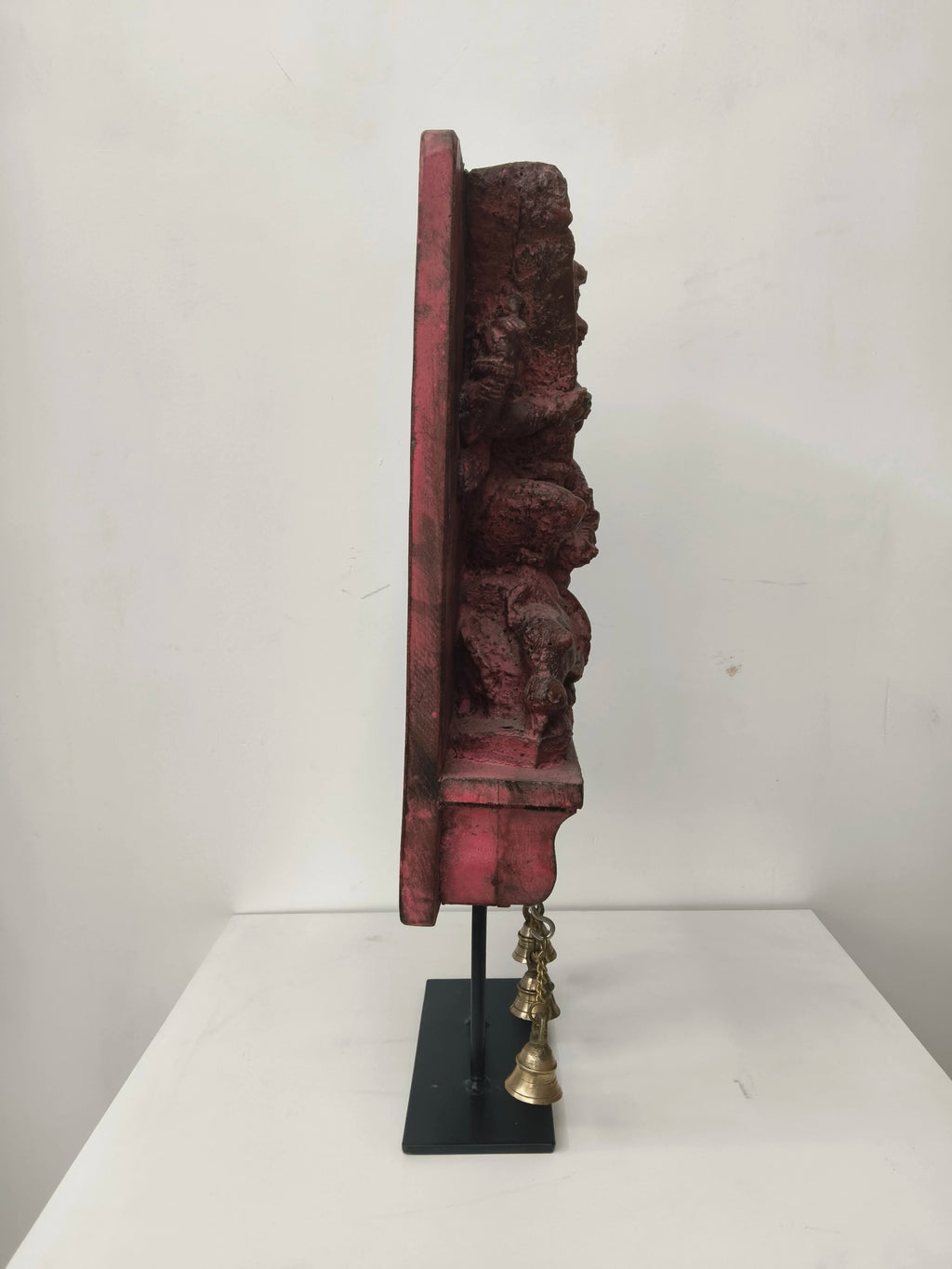 Side view of large wooden Mahishasura Mardini sculpture with hanging brass bells