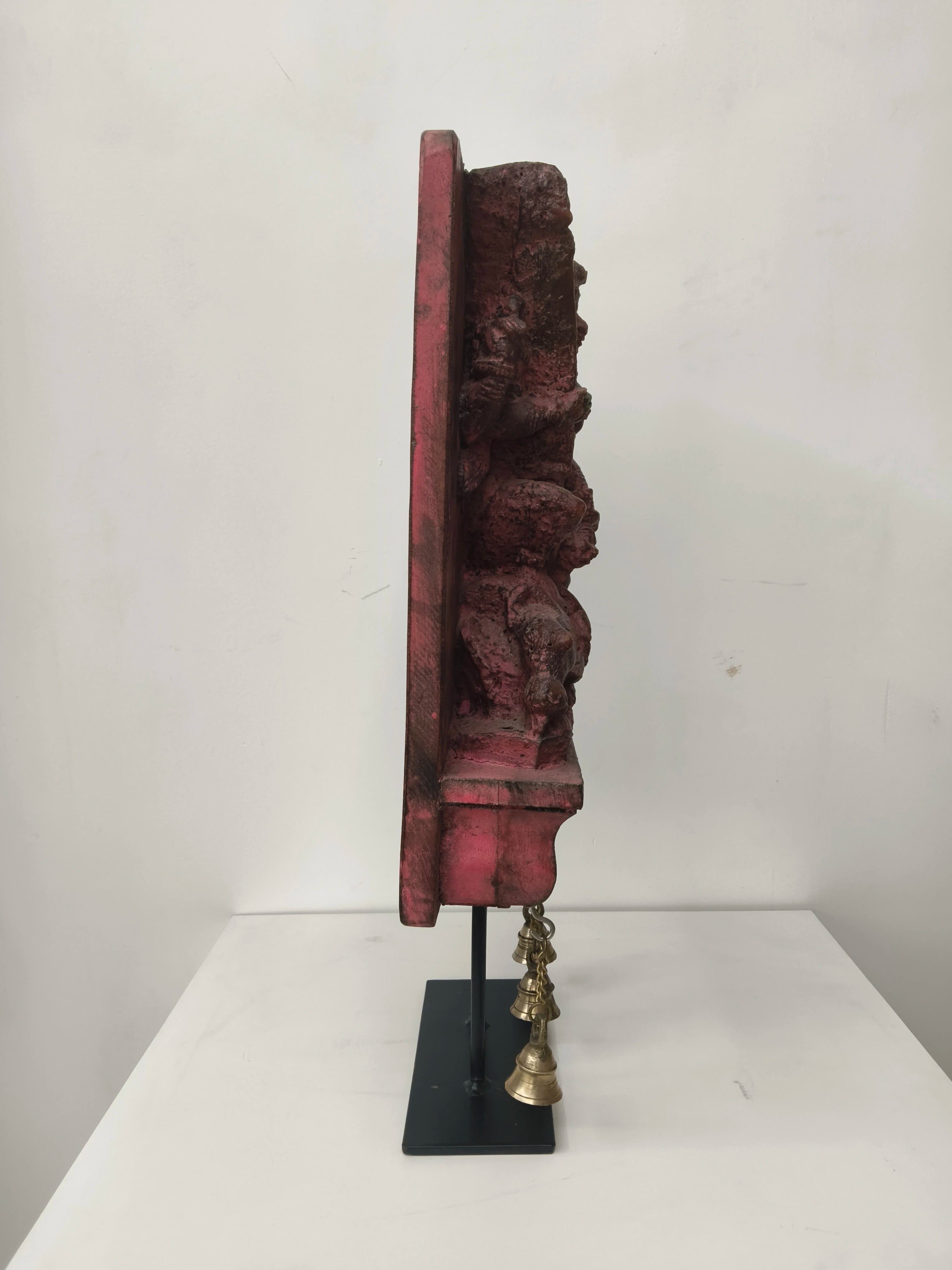 Side view of large wooden Mahishasura Mardini sculpture with hanging brass bells